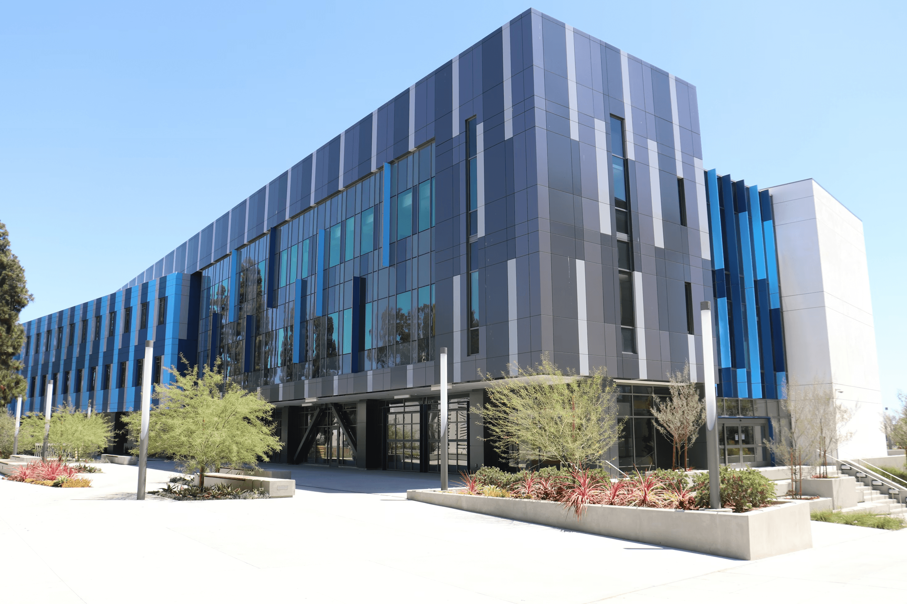 Modern office building with blue and gray facade and landscaped courtyard