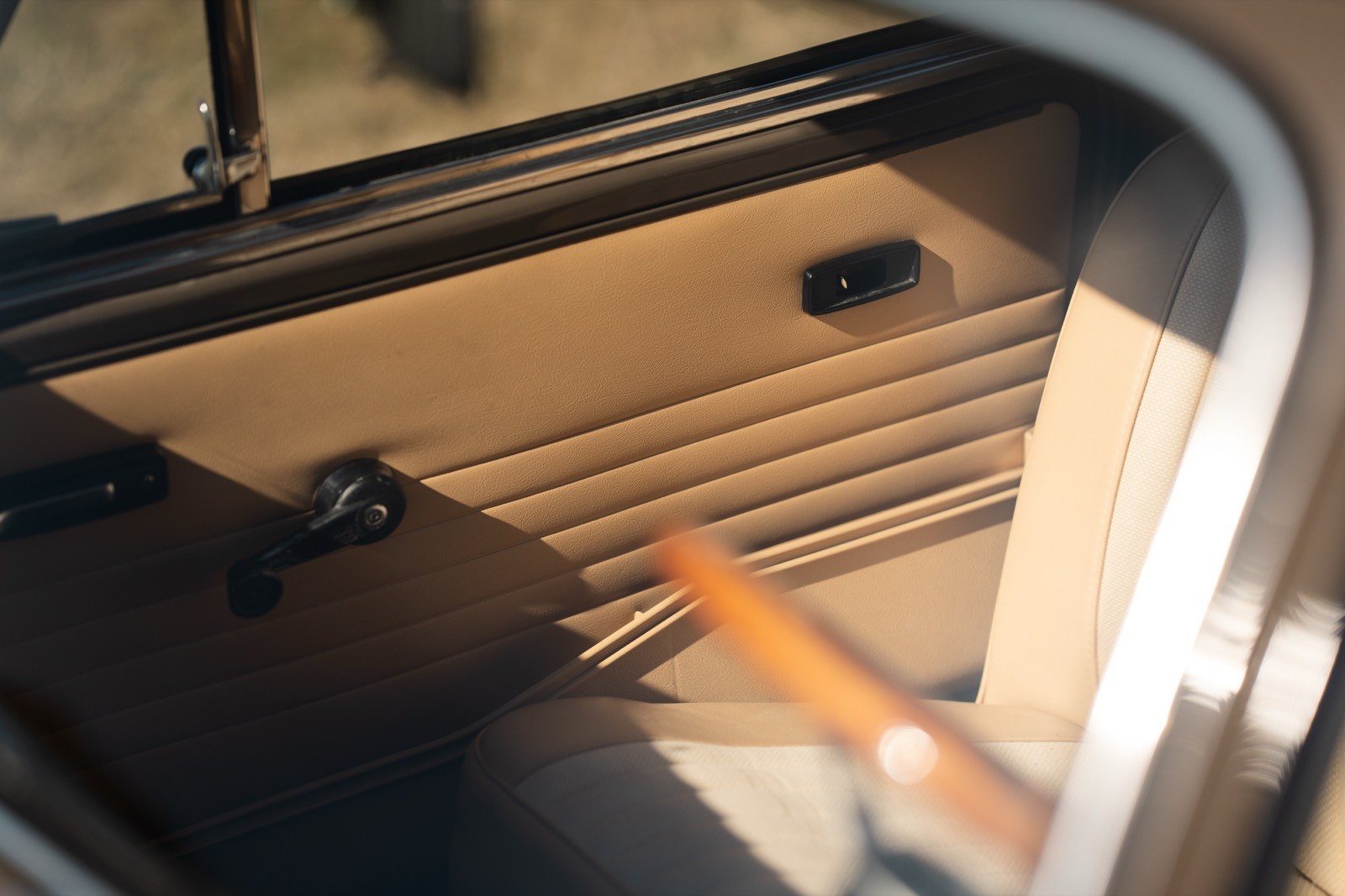 Close-up of a car's trunk interior, featuring a wooden plank and textured flooring. Light illuminates the space.