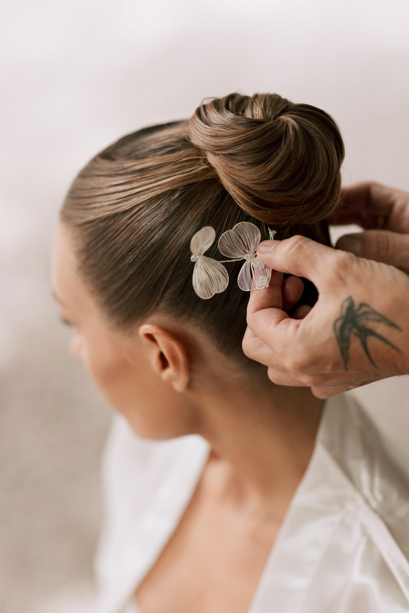 Sposa che indossa fermaglio floreale fra i capelli raccolti, dettaglio preparativi matrimonio a Villa Ferrari