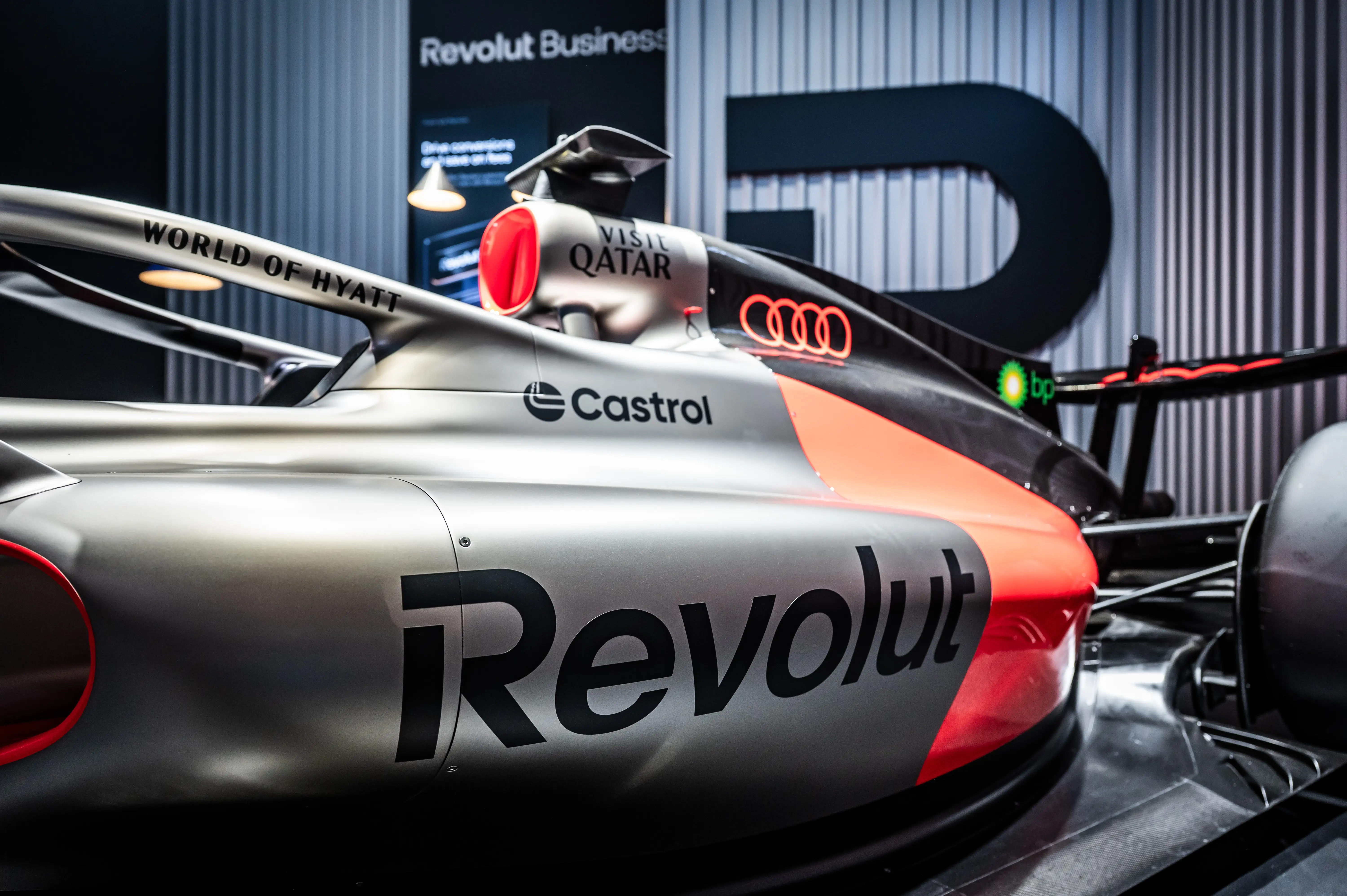 Close-up of the silver Formula 1 show car with Revolut branding in front of the dark booth wall.