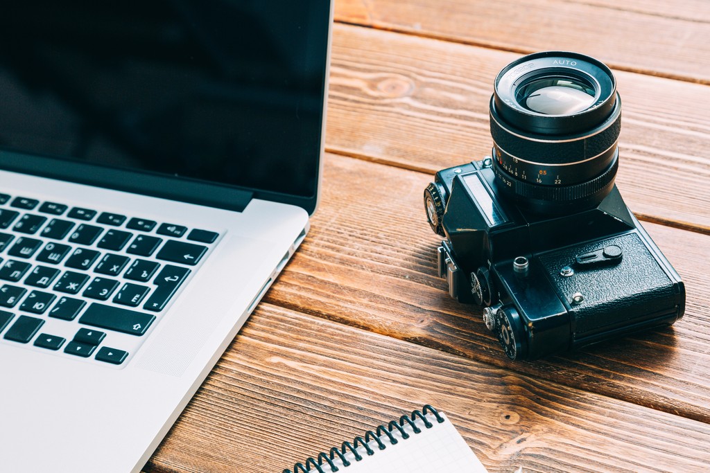 Vintage camera and laptop on wooden desk for wedding photography business