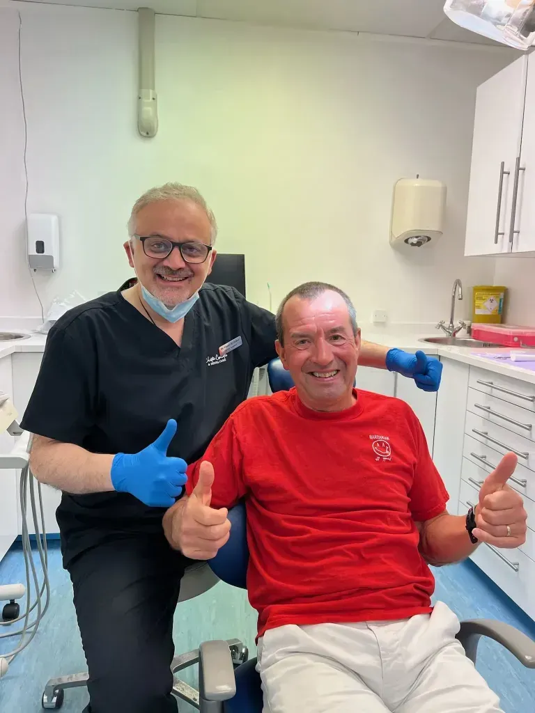 Dr Yasser and his happy patient, both smiling and putting their thumbs up.