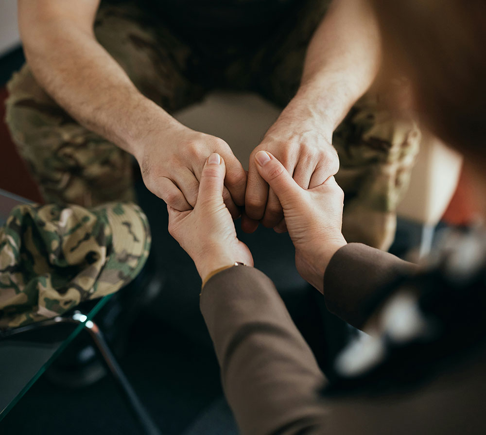 Two people clasping hands in a gesture of support or comfort.