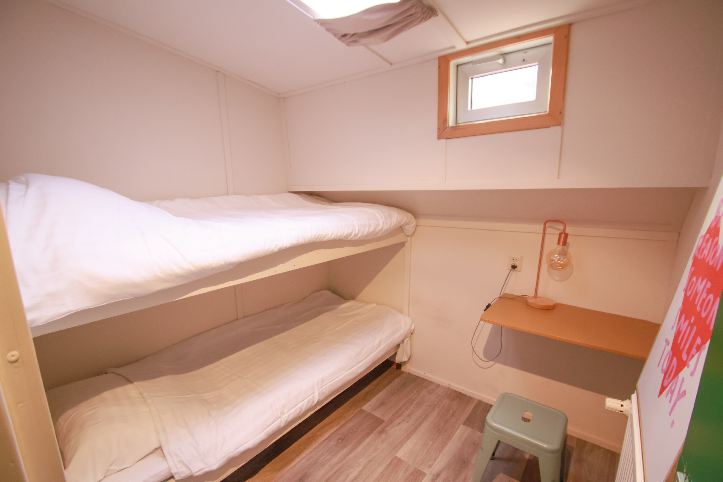 Beige upholstered bed with patterned pillows and ottomans