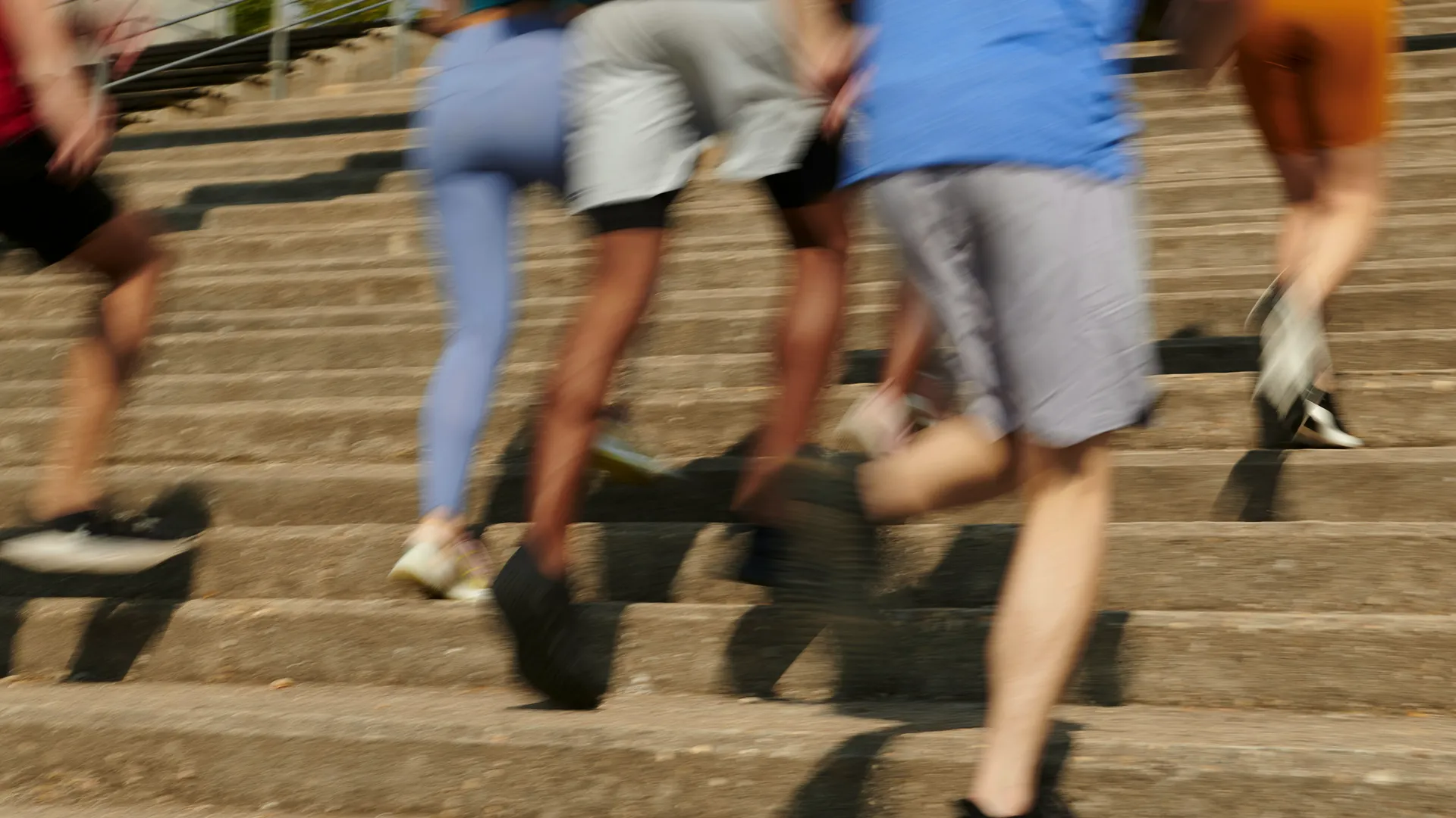 Group of adults running up outdoor stairs to improve cardiovascular fitness, endurance, and long-term health through regular exercise.