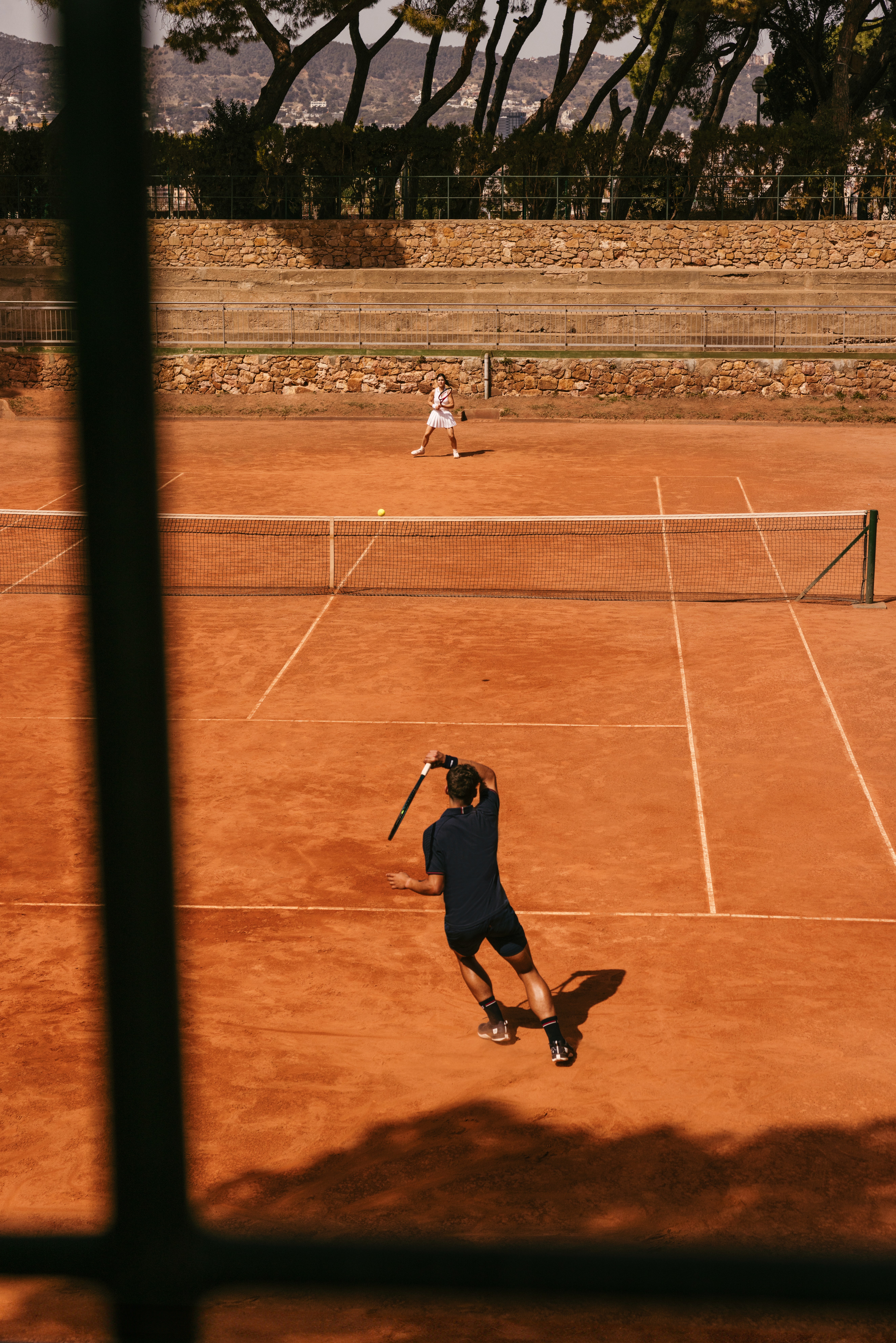 Photo d'ambiance du lookbook de Wilson Courstyle ou l'on voit une partie de tennis en extérieur sur terre battue à Barcelone
