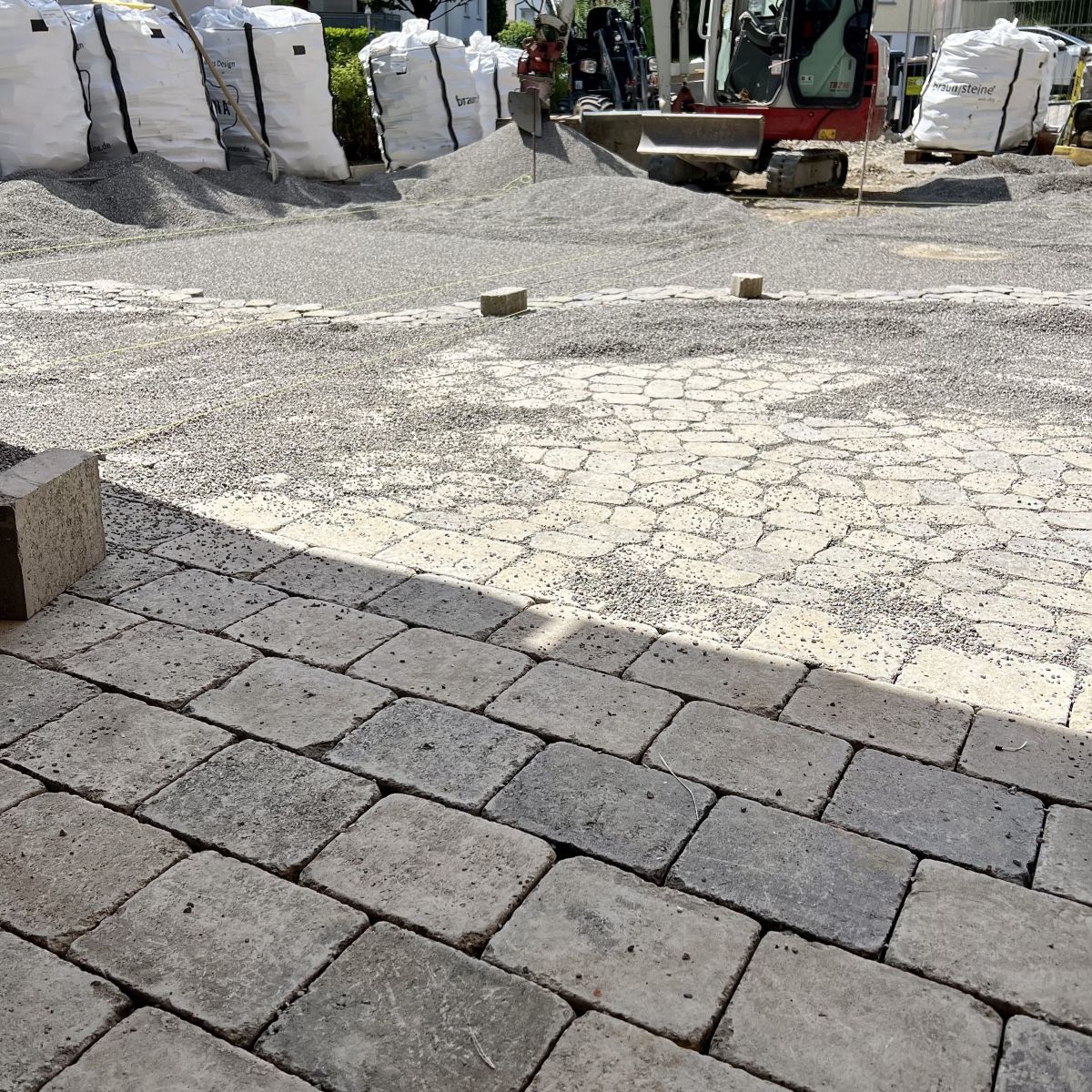Neu verlegtes Pflaster in einem Außenbereich, mit Minibagger im Hintergrund, Fachbetrieb Klingenstein.