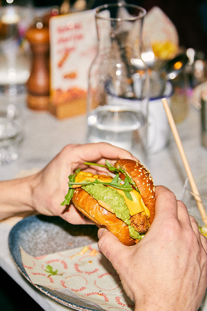 Hands holding a fried chicken burger