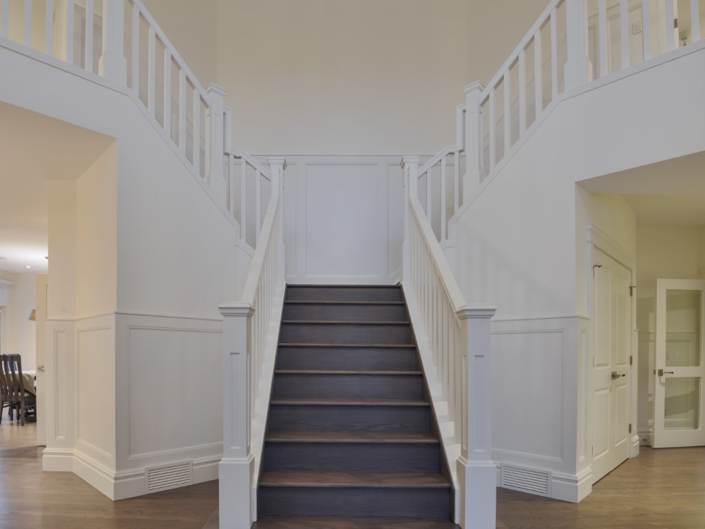 Image of Staircase with dark wood steps and white railings in a KHD Homes design-build interior renovation project.
