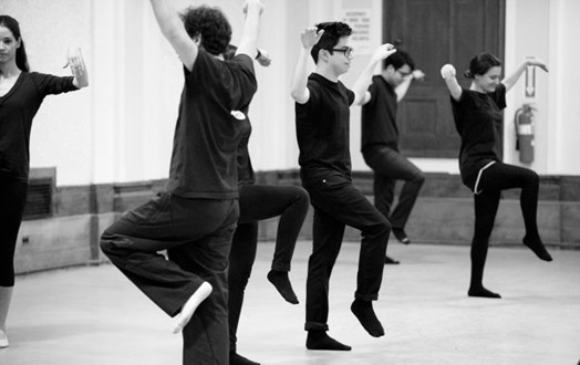 A black and white photo of a group of people doing some kind of exercise in a hall.