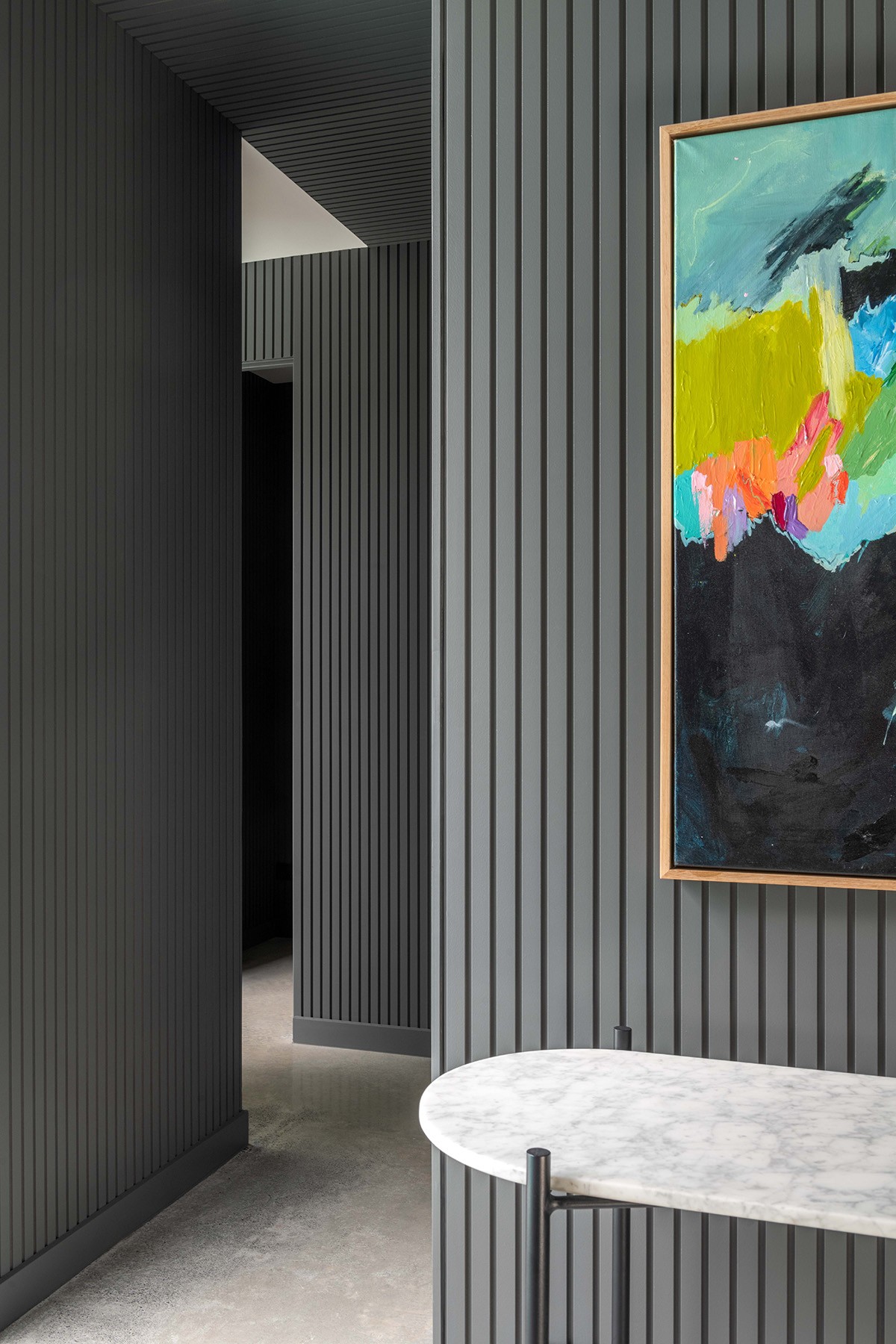 Interior circulation space at The Stables with vertically lined walls, a sculptural artwork, and filtered light shaping a quiet, transitional zone.