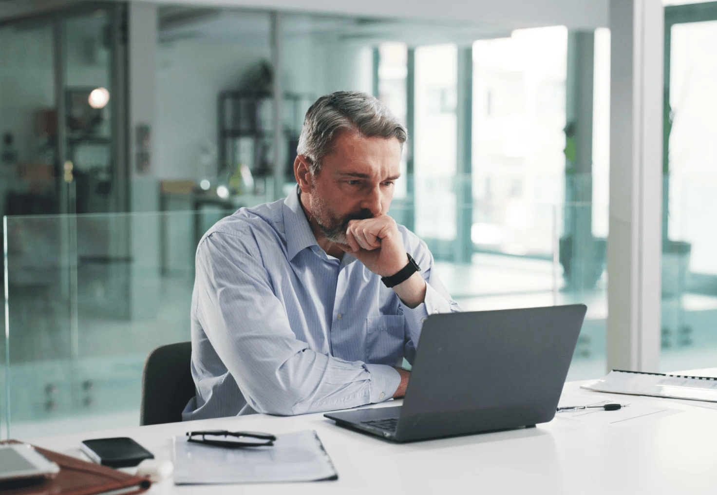 Middle-aged man in a bright office concentrating on his laptop, symbolising how manual oversight of high-value ASINs can slow response times—reinforcing the need for autonomous, real-time PPC management systems like Autron.