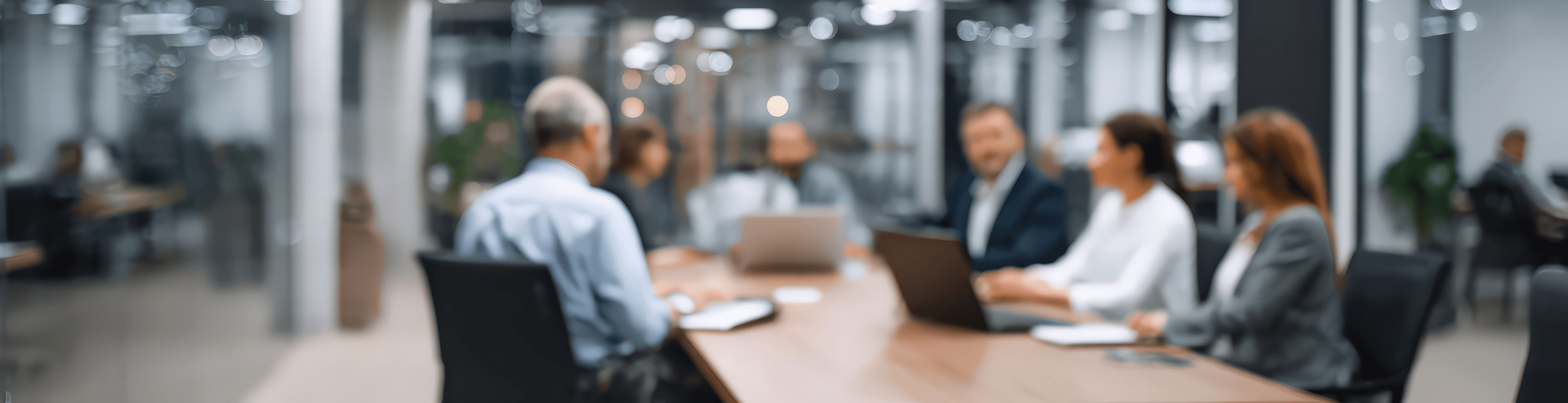 Soft-focus image of senior professionals in a modern office meeting around a conference table, representing governance, strategic alignment, and organisational decision-making.