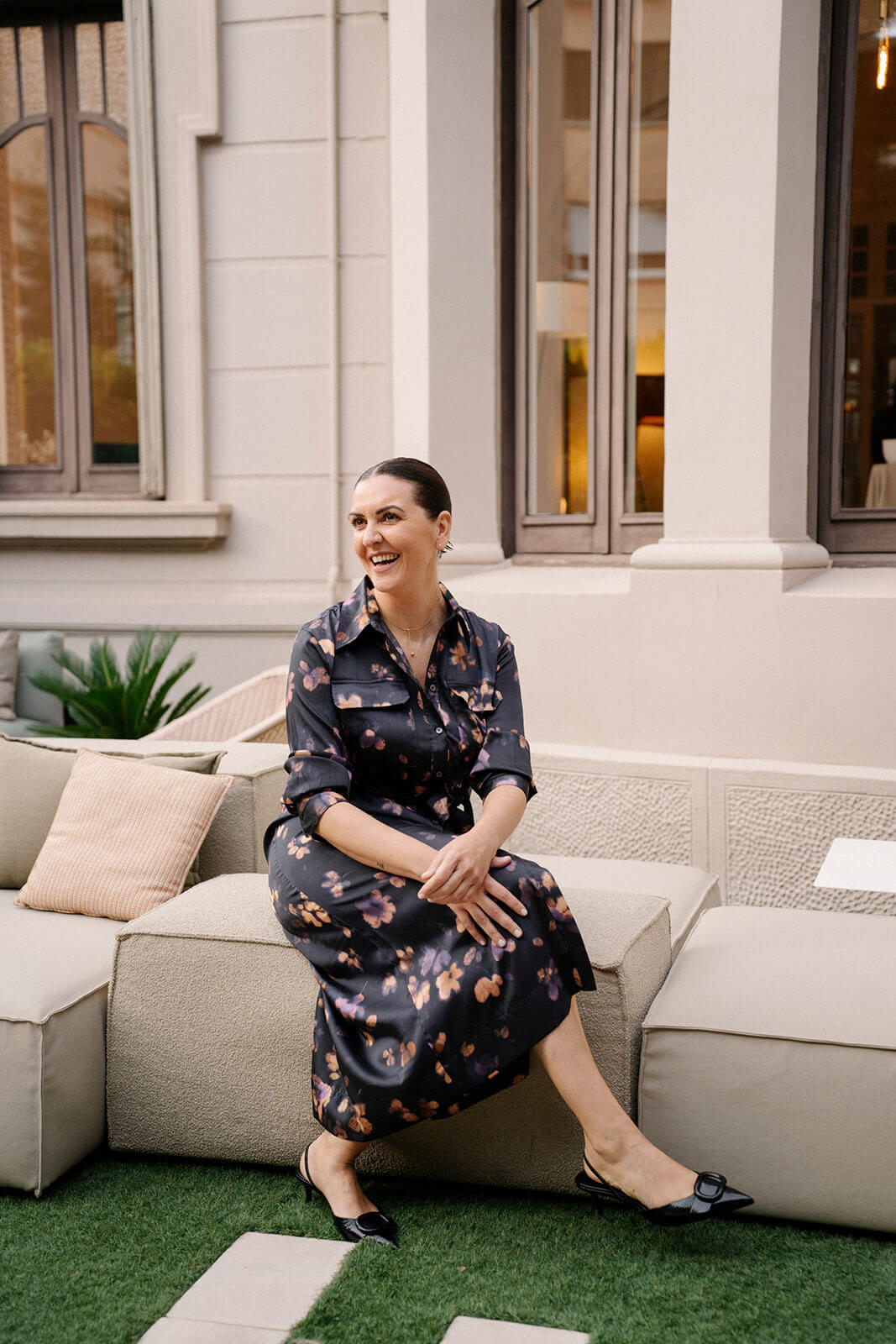 Mujer sentada en un sofá exterior, sonriendo