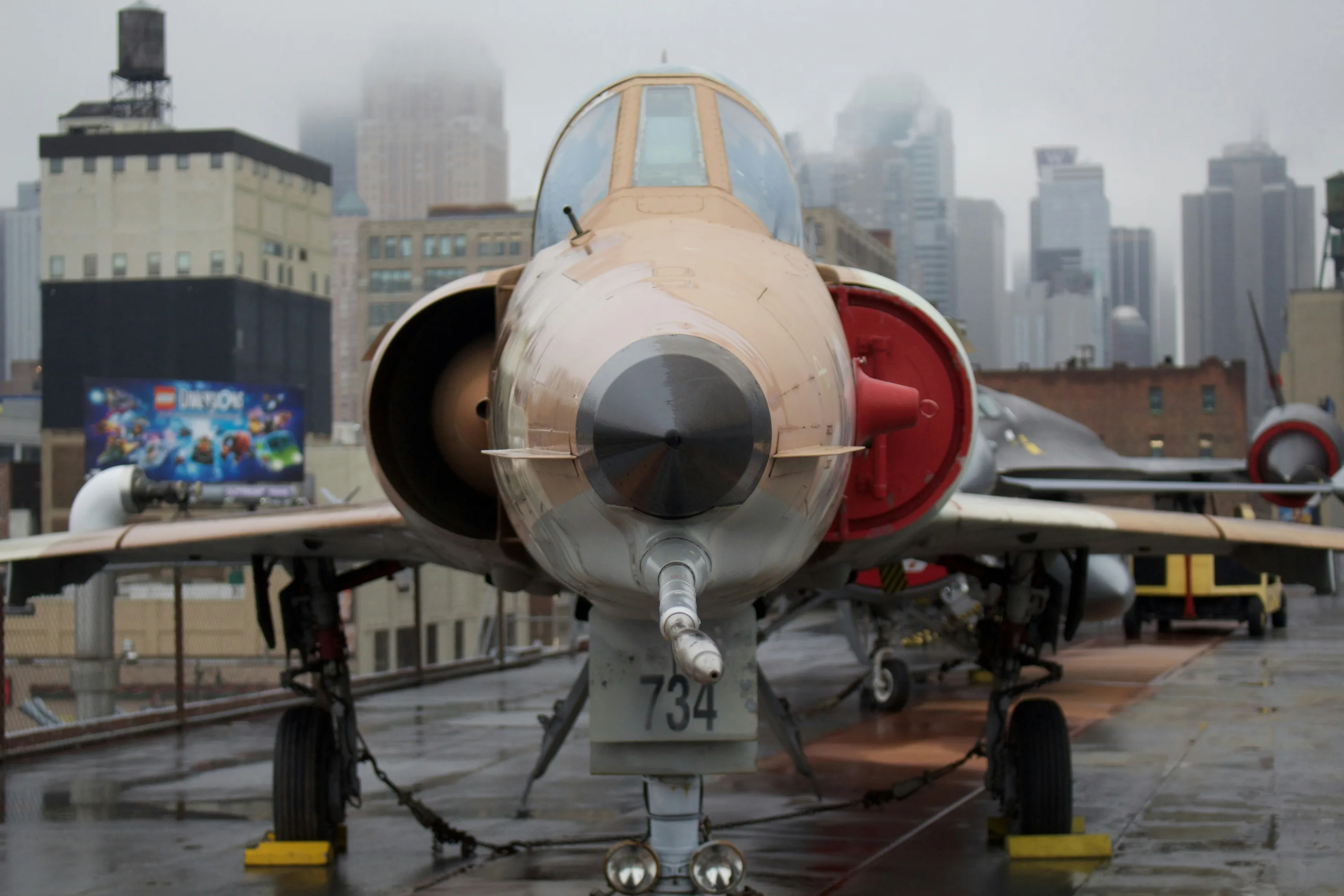 Looking straight on at the nose of a fighter jet on the flight deck of the Intrepid aircraft carrier.