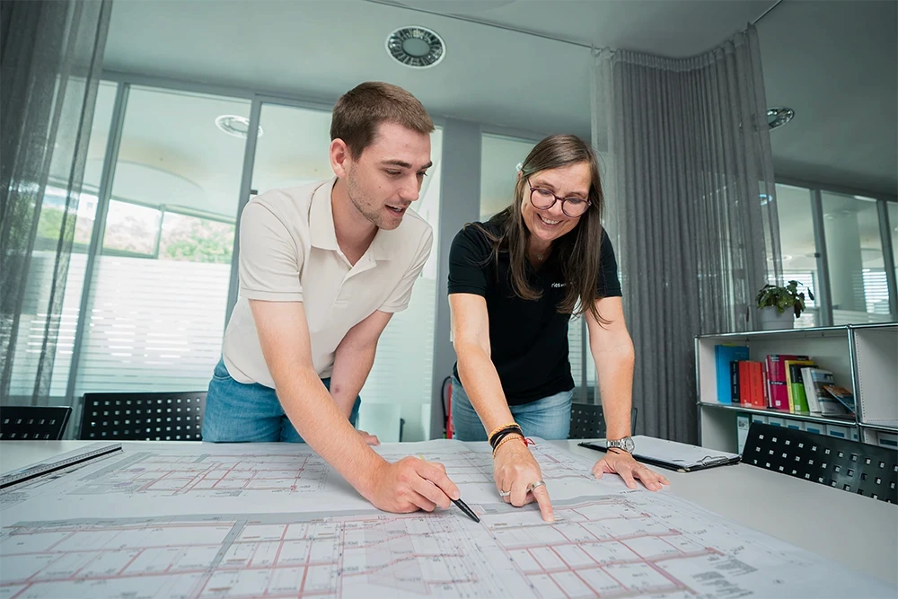 Architektin und Architekt von Fries Architekten besprechen gemeinsam einen Grundriss und entwickeln Lösungen für ein Bauprojekt.