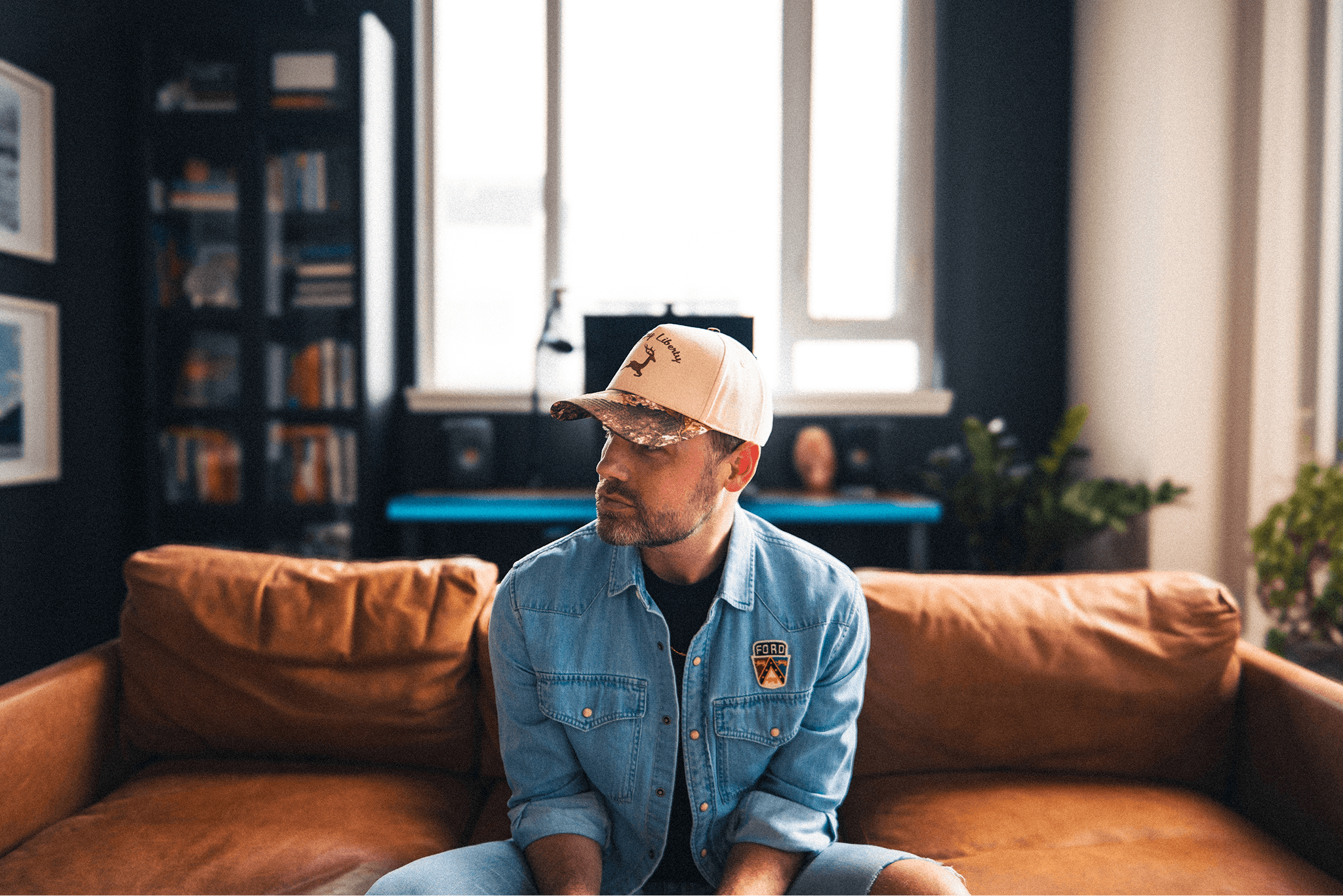 Designer Chadd Weston sitting on a stool looking out the window during a photo shoot on Manhattan