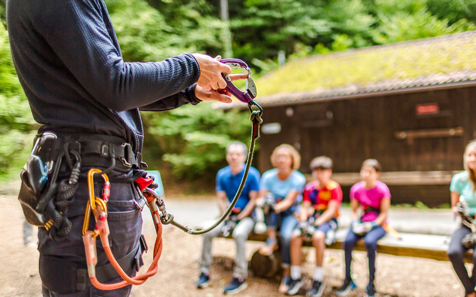 Instructor demonstrating safety gear at Ropes Park Interlaken to a seated group.
