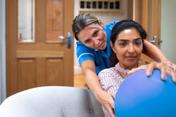 Physical therapist assisting a woman with core-strengthening therapy using an exercise ball.