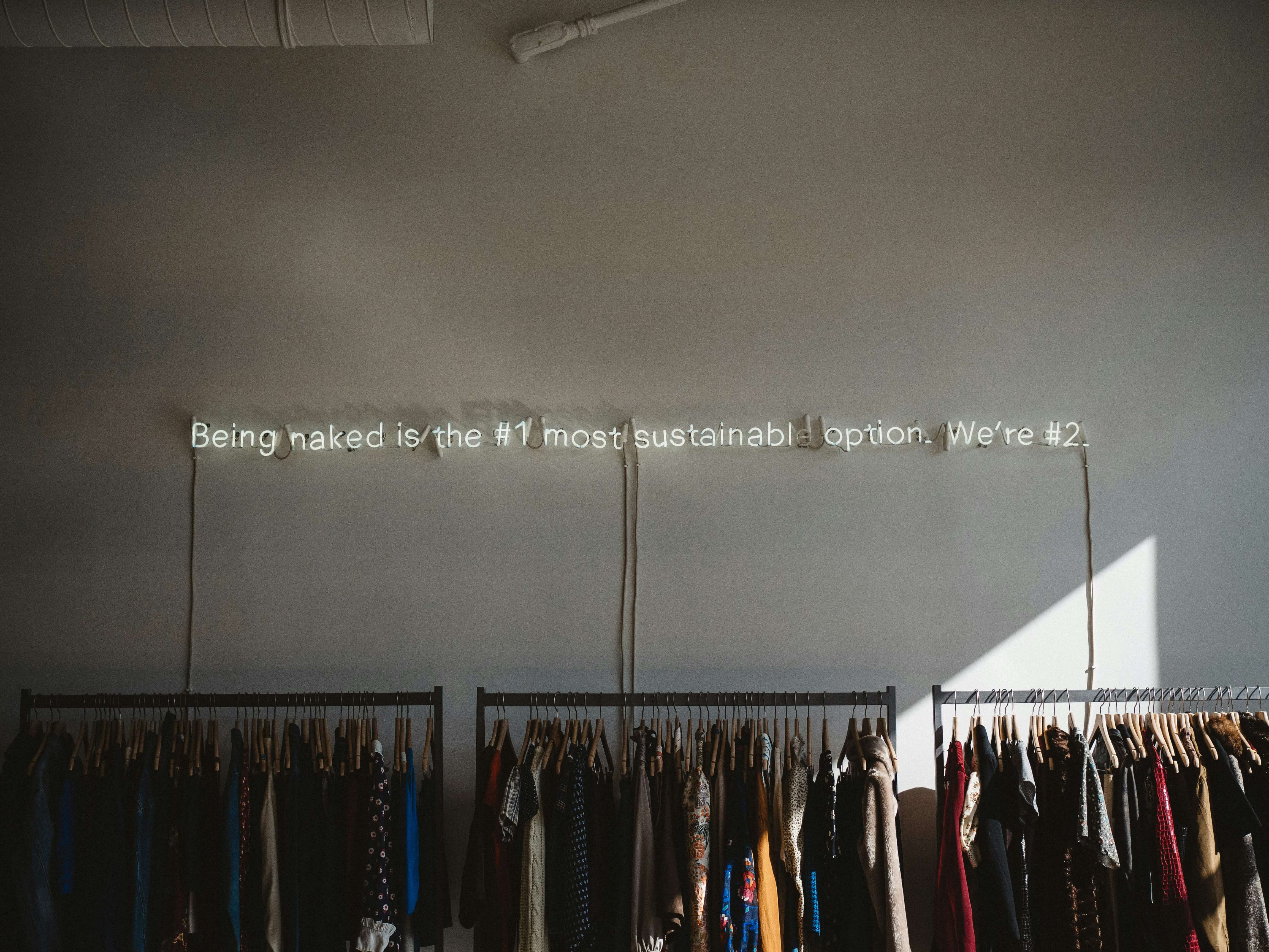 3 racks full of clothes against a grey background.