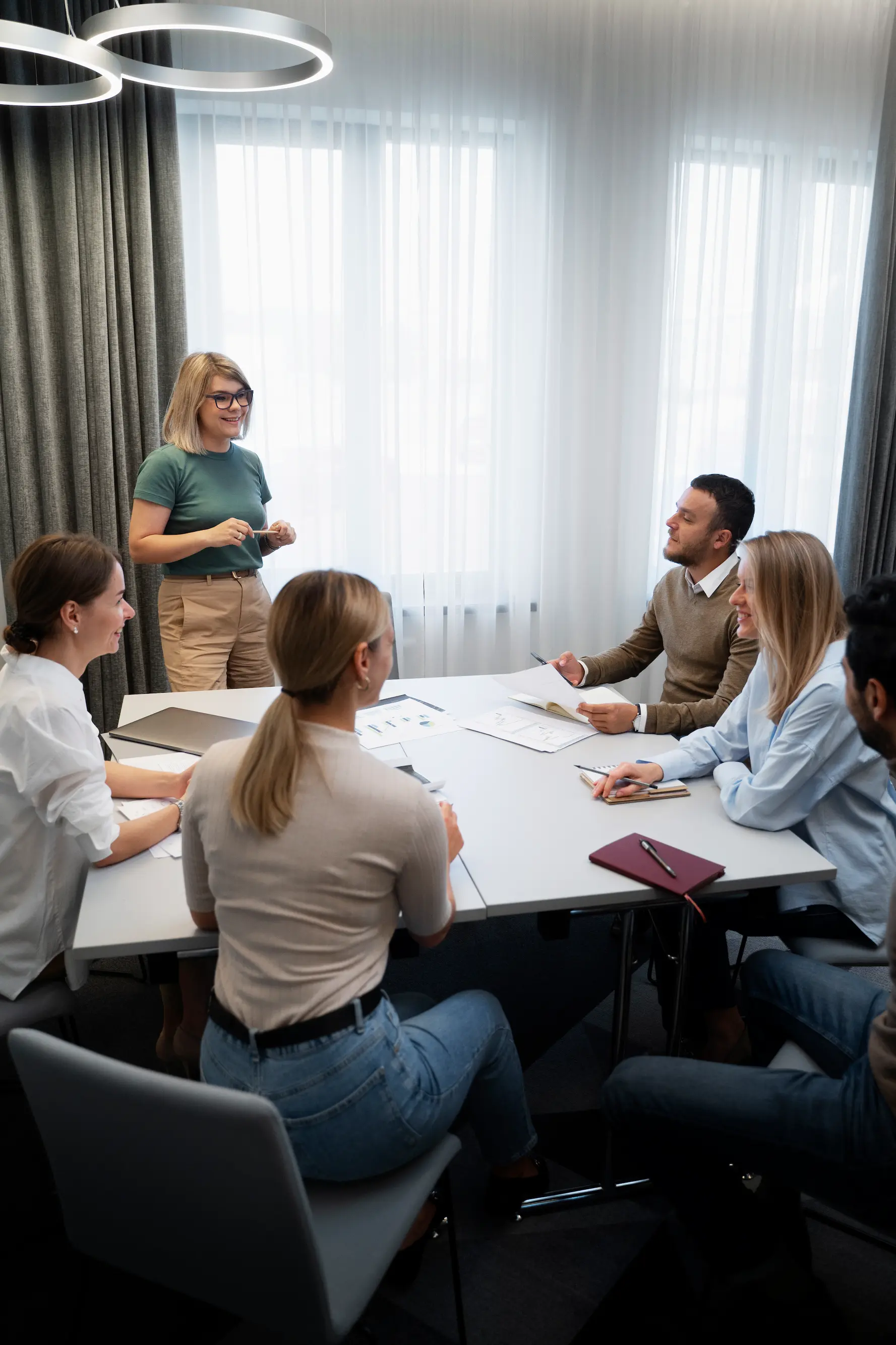 Ein Team aus mehreren Personen sitzt in einem modernen Besprechungsraum und bespricht gemeinsam Unterlagen und Konzepte.