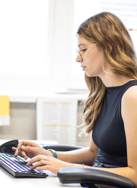 Women typing at a keyboard, sitting at a desk.