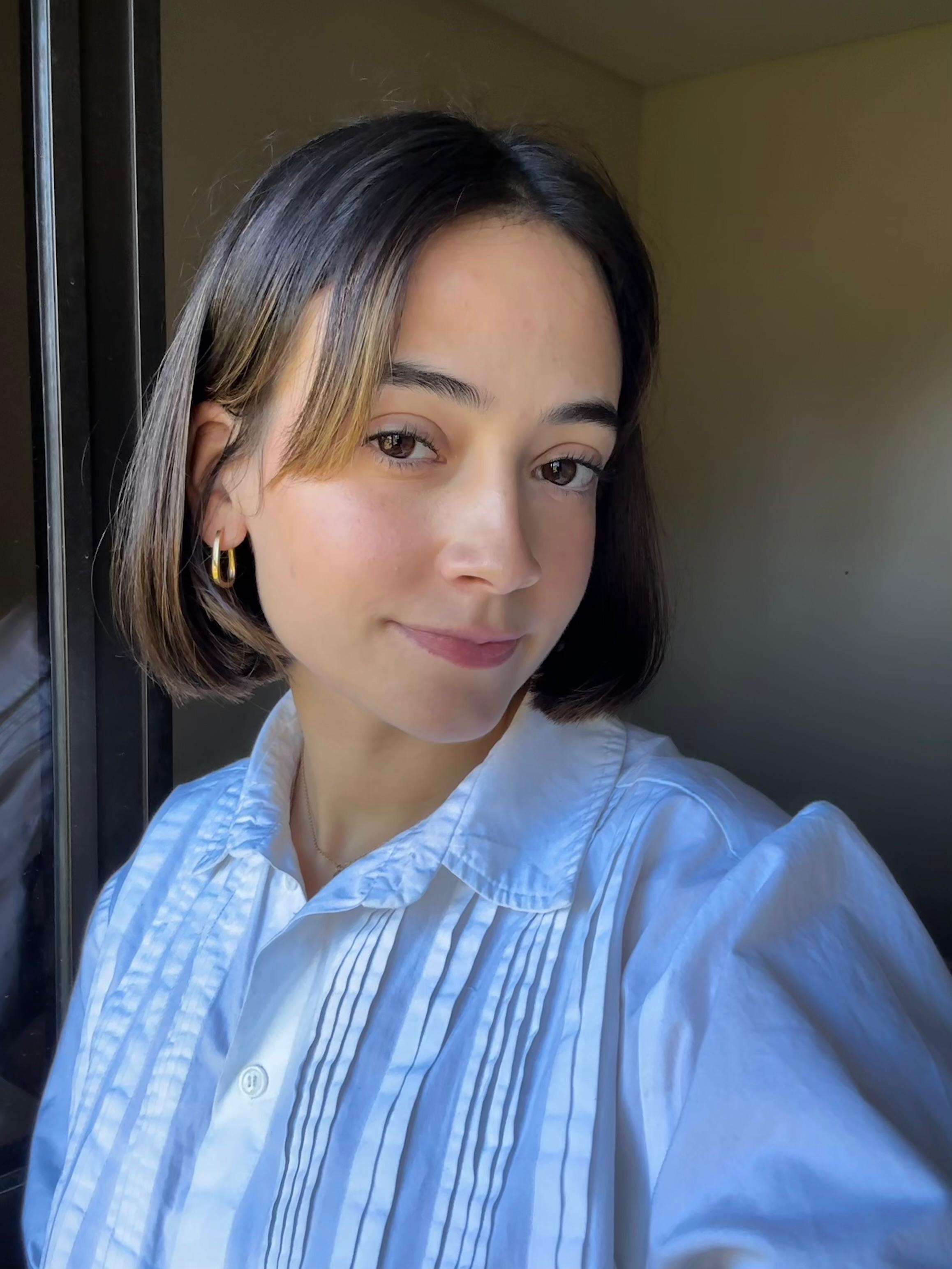 A thoughtful young person with dark hair gazes to the side, captured in soft black and white lighting.
