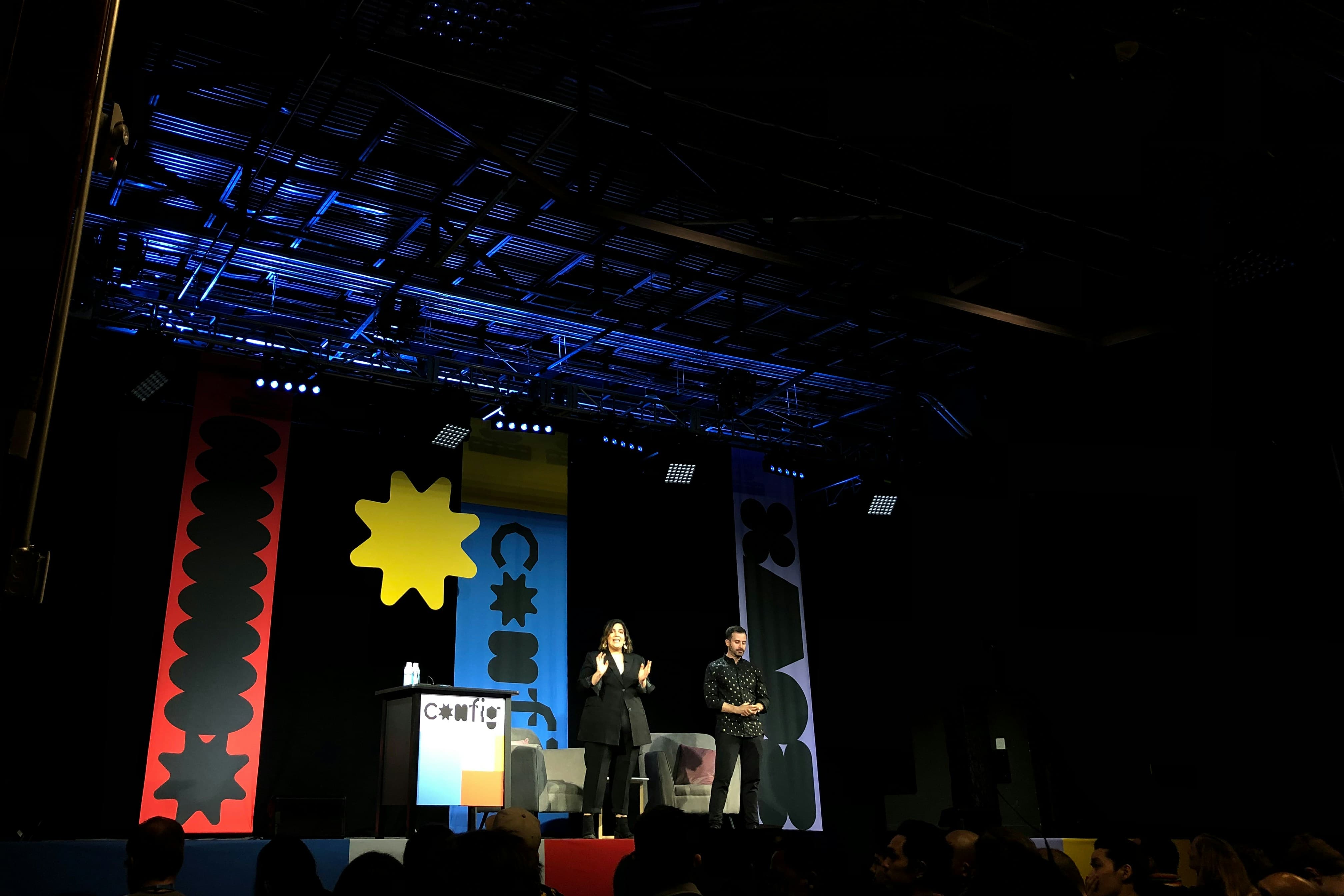 A man and woman standing on a stage speaking in a conference
