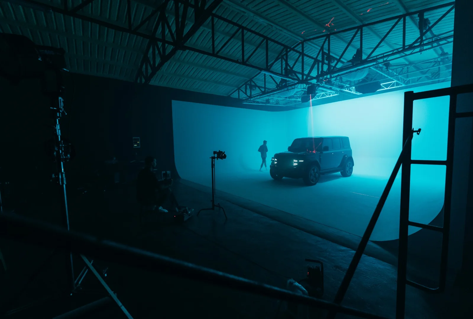 Chery V23 in teal RGB light and haze on the cyclorama, with the crew in the foreground