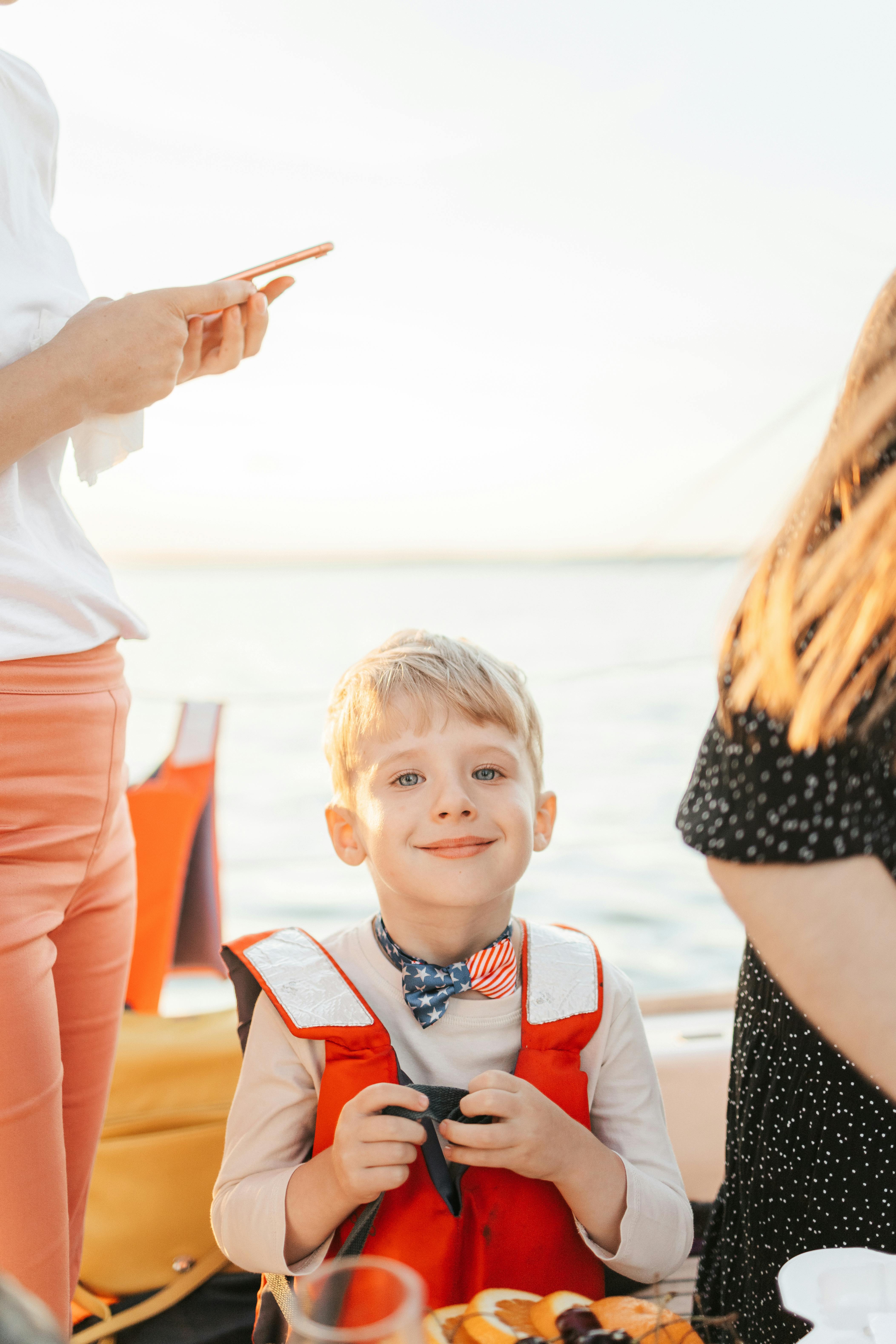 Family relaxing on a sandy beach with boats offshore.