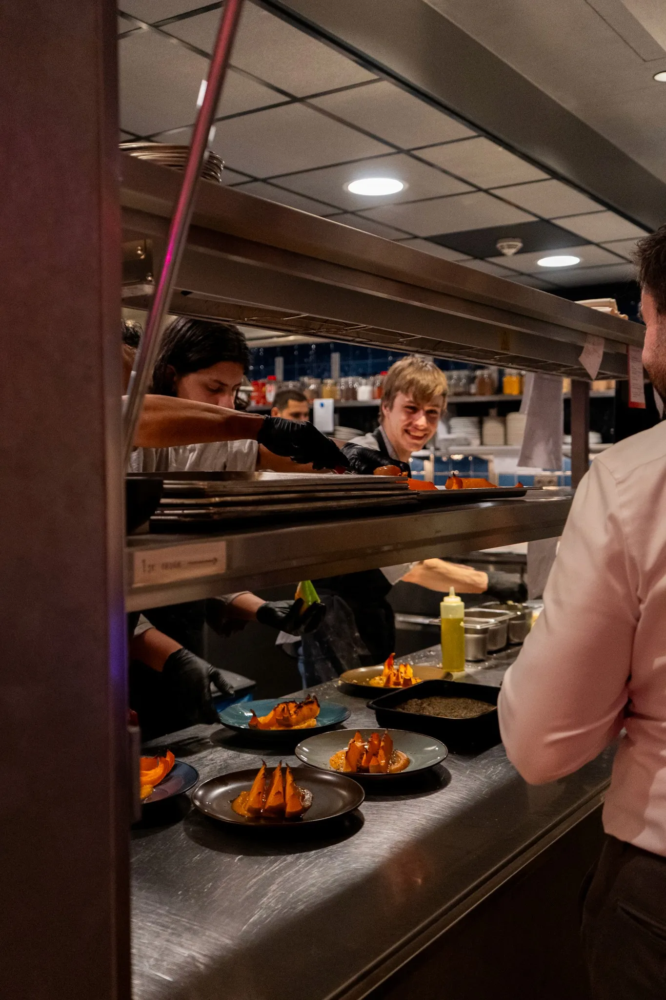 A person stands at a buffet, selecting food from a variety of dishes displayed on a serving counter.