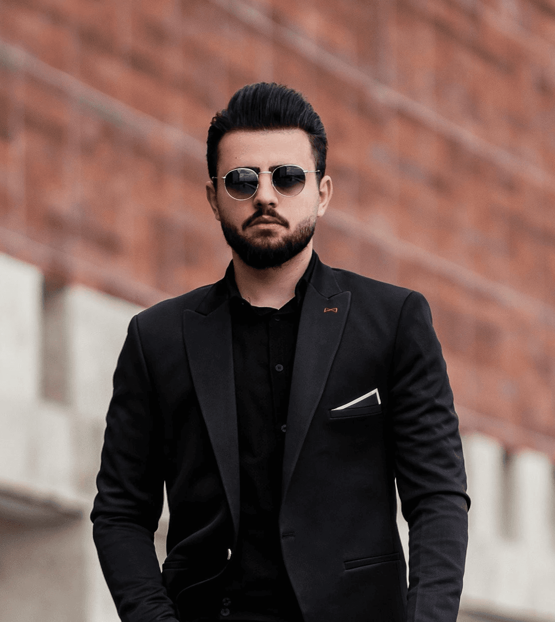 man in black suit jacket and black pants standing on gray concrete floor during daytime