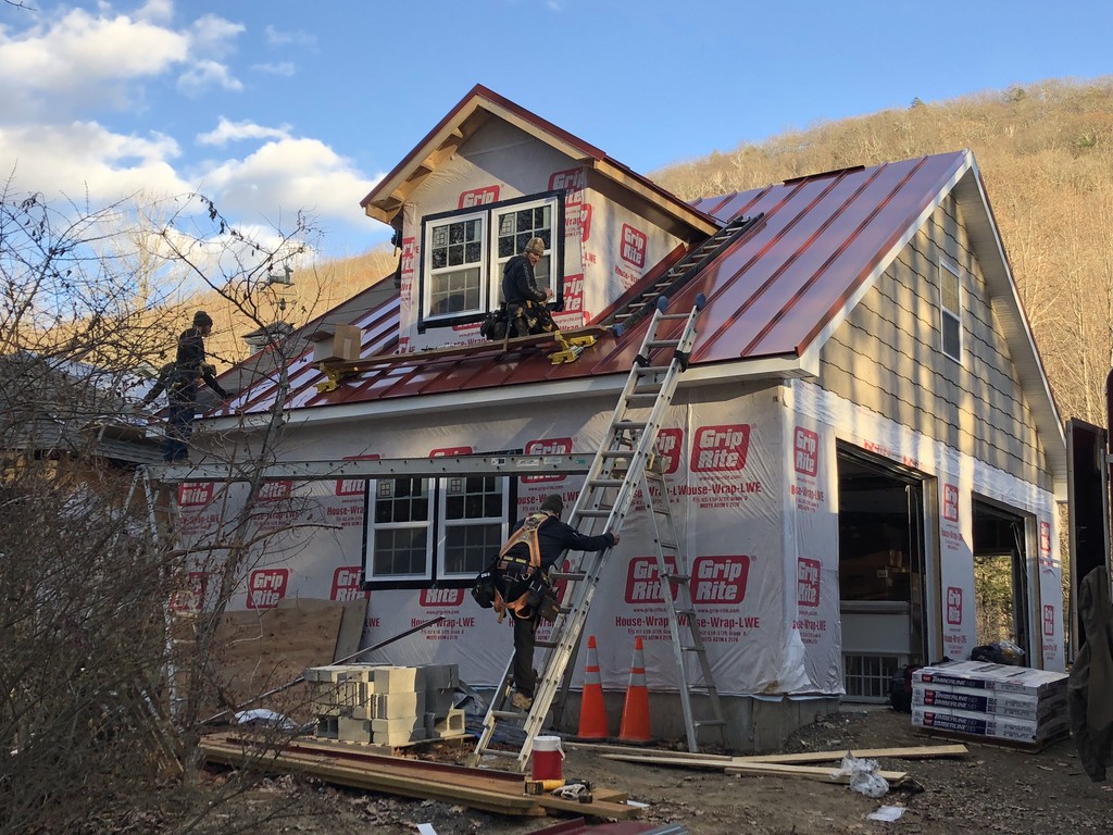Custom home under construction with metal roof and dormer addition, showcasing quality framing and exterior work by Casali Companies