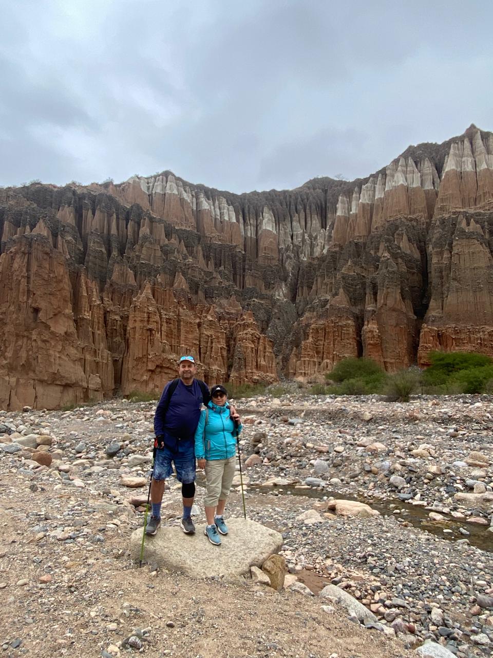 Mujer sentada sobre un tronco frente a una cascada doble en un bosque frondoso de Argentina.