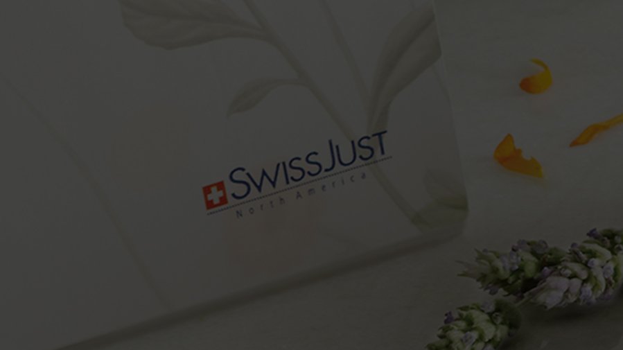 Text reads "SwissJust North America" on a soft-focus background with delicate leaves and scattered yellow petals, conveying a calm and natural theme.