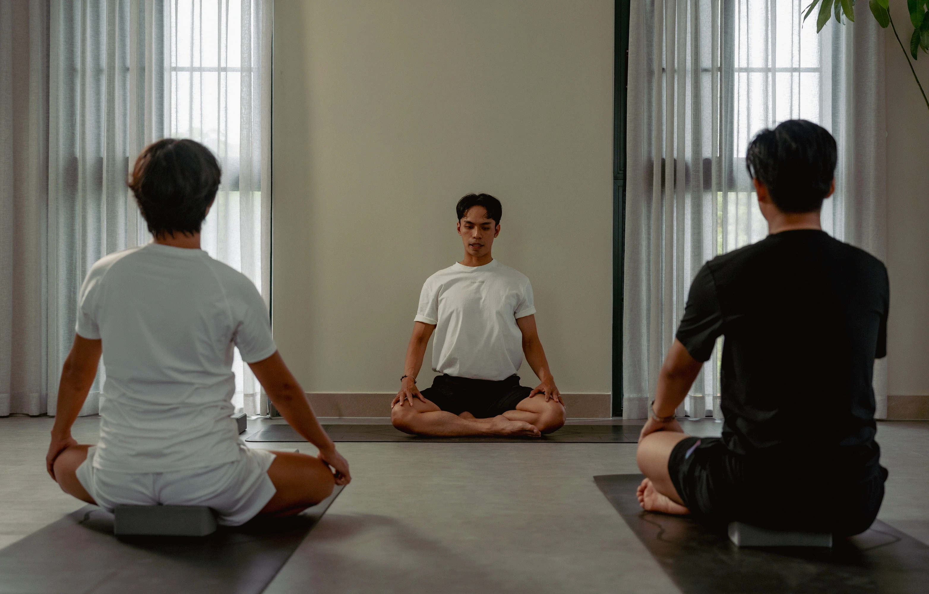 Women doing yoga poses in a bright studio, focusing on strength and flexibility training during a group fitness session.