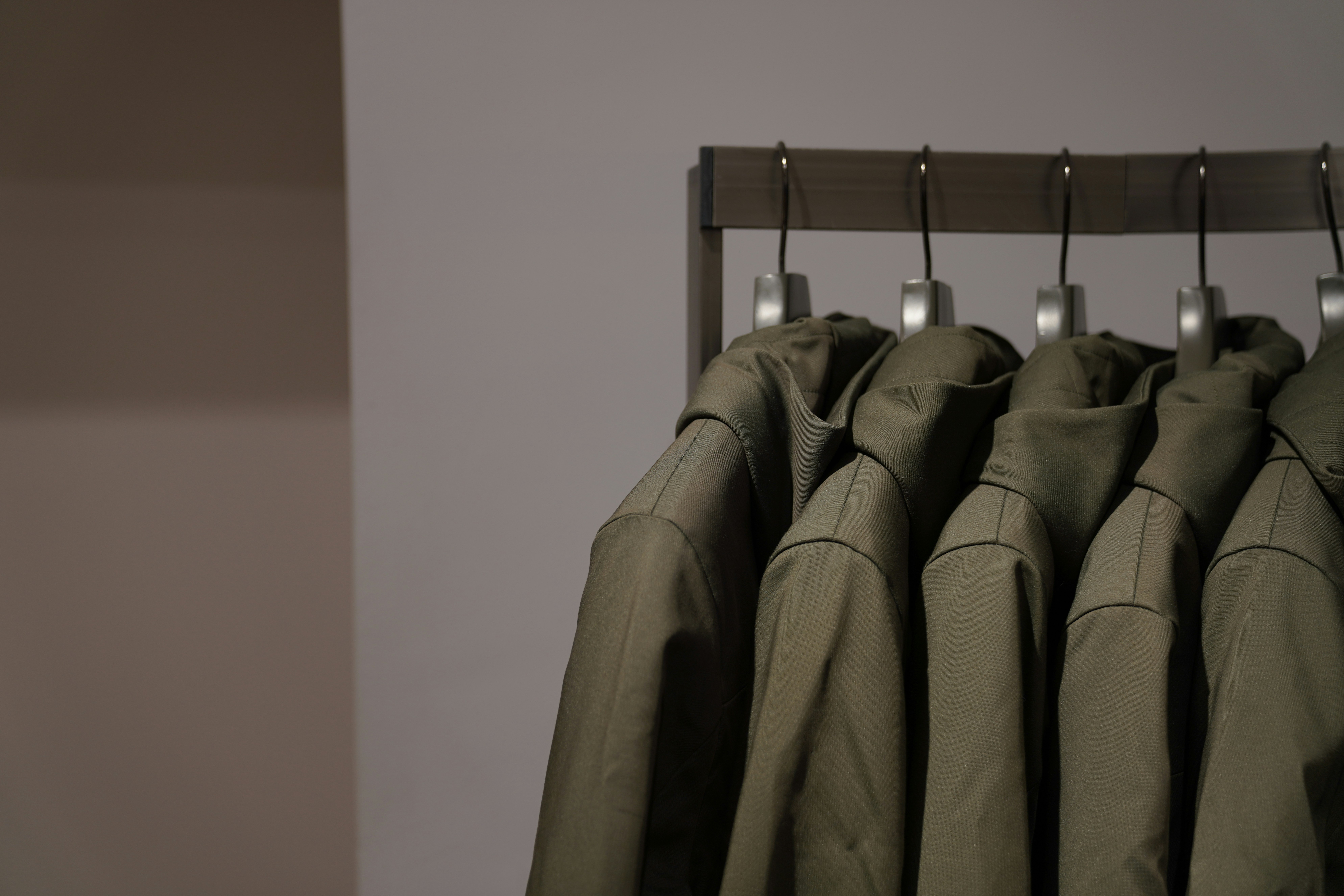 a row of green suits hanging on a rail
