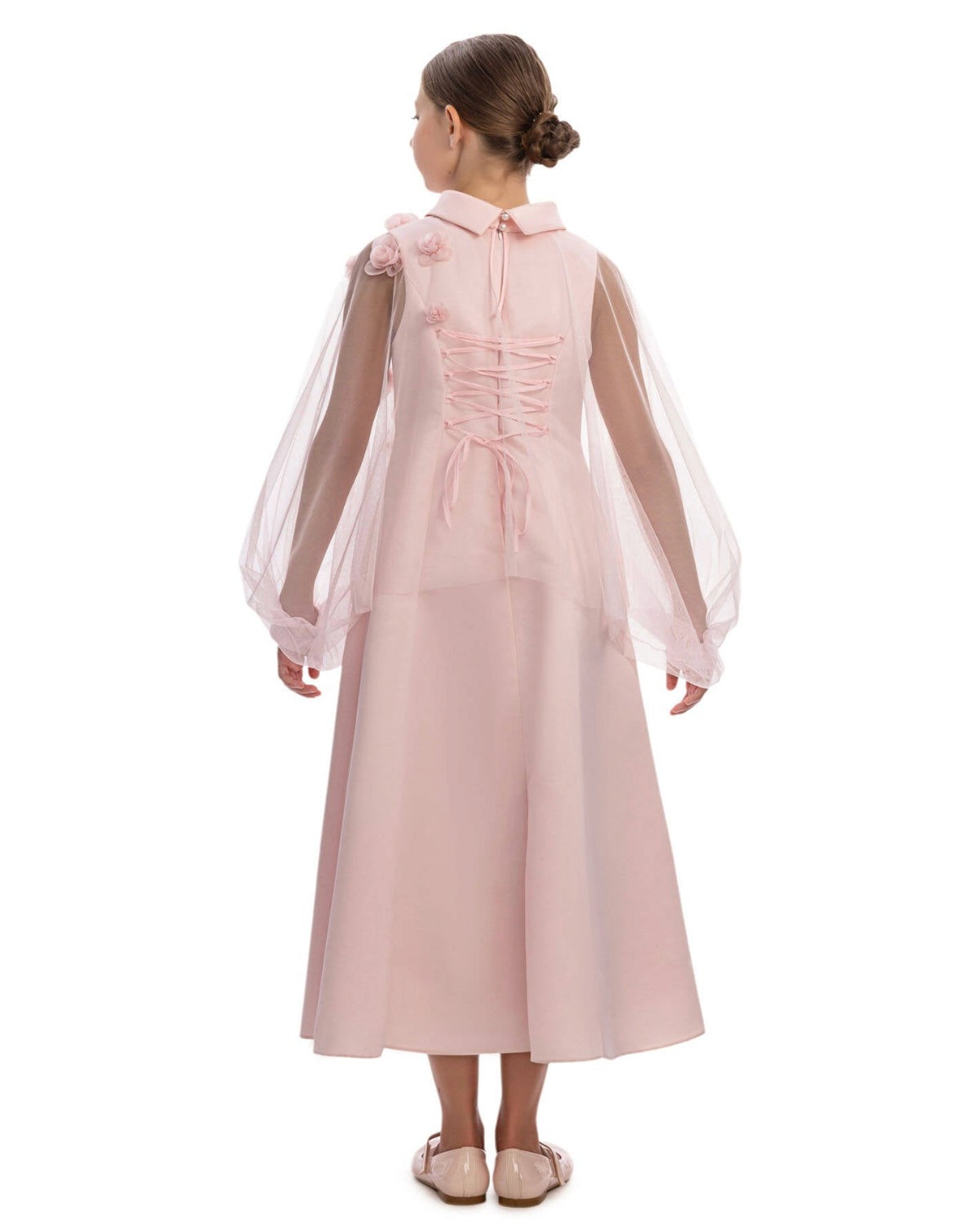 Pink dress with sheer sleeves worn by a model on a white background