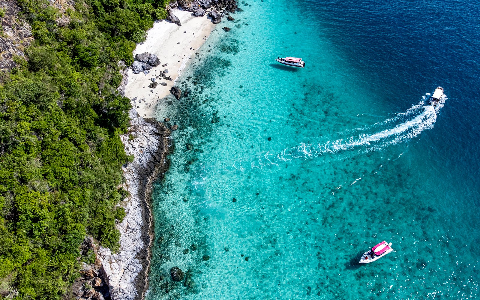 Ilmakuva veneistä lähellä turkooseja vesiä ja kalliorantaa Nemo Islandilla, Pattayalla.