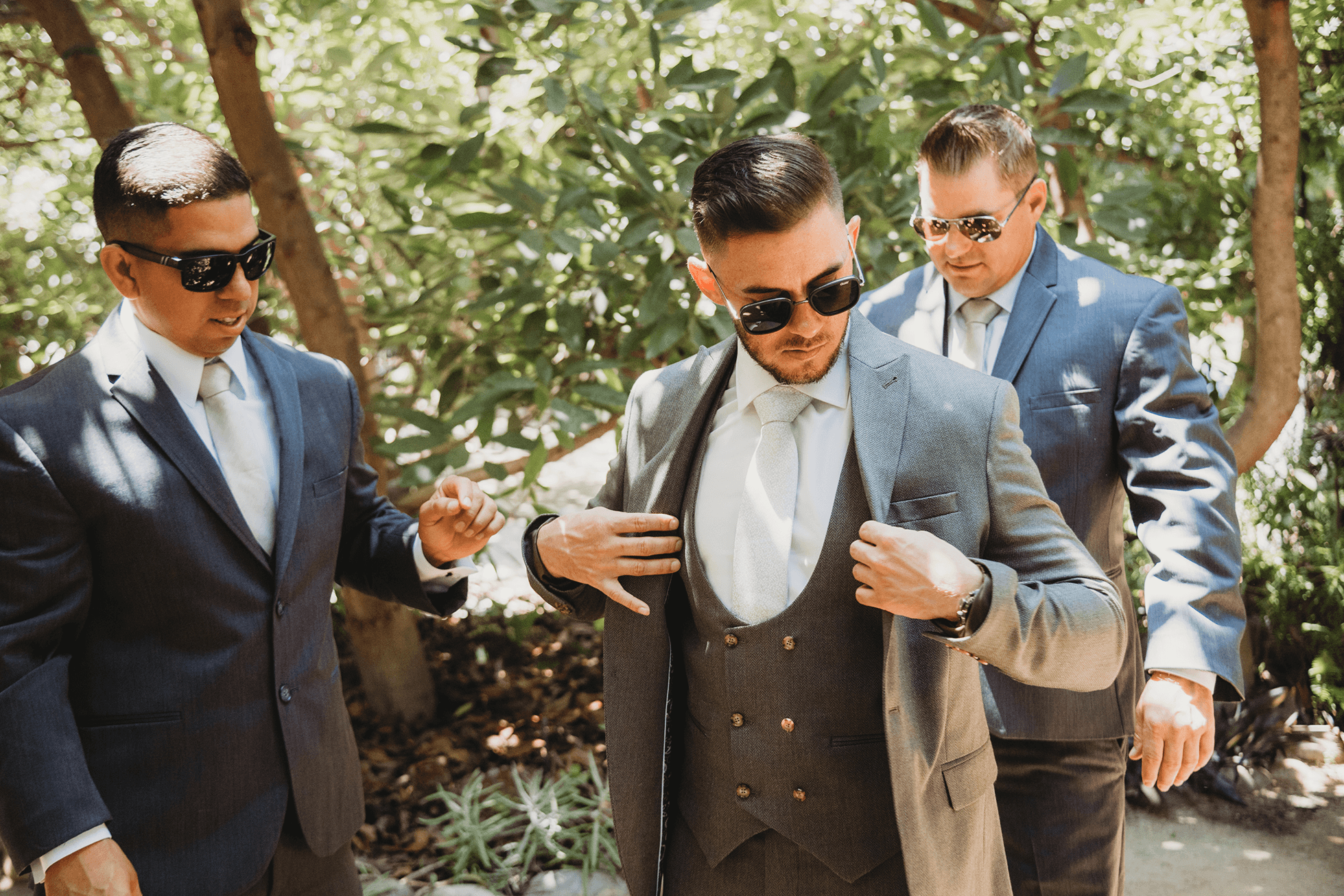 Best man helping groom into jacket with paisley lining