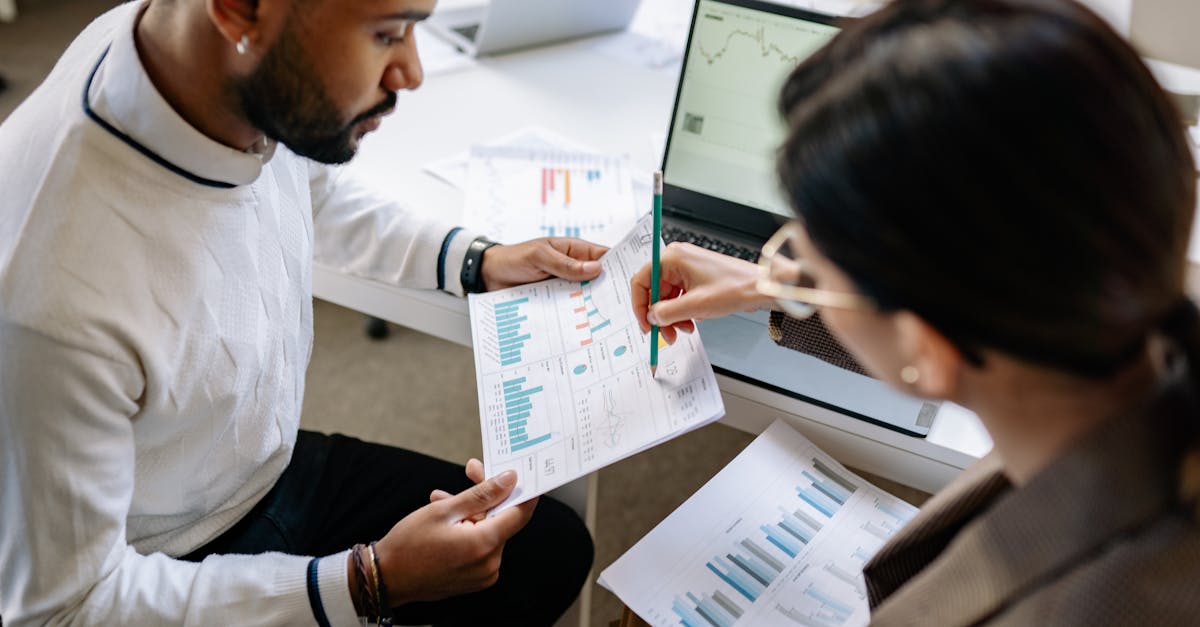 Two professionals reviewing data and graphs in a modern office setting for analysis.
