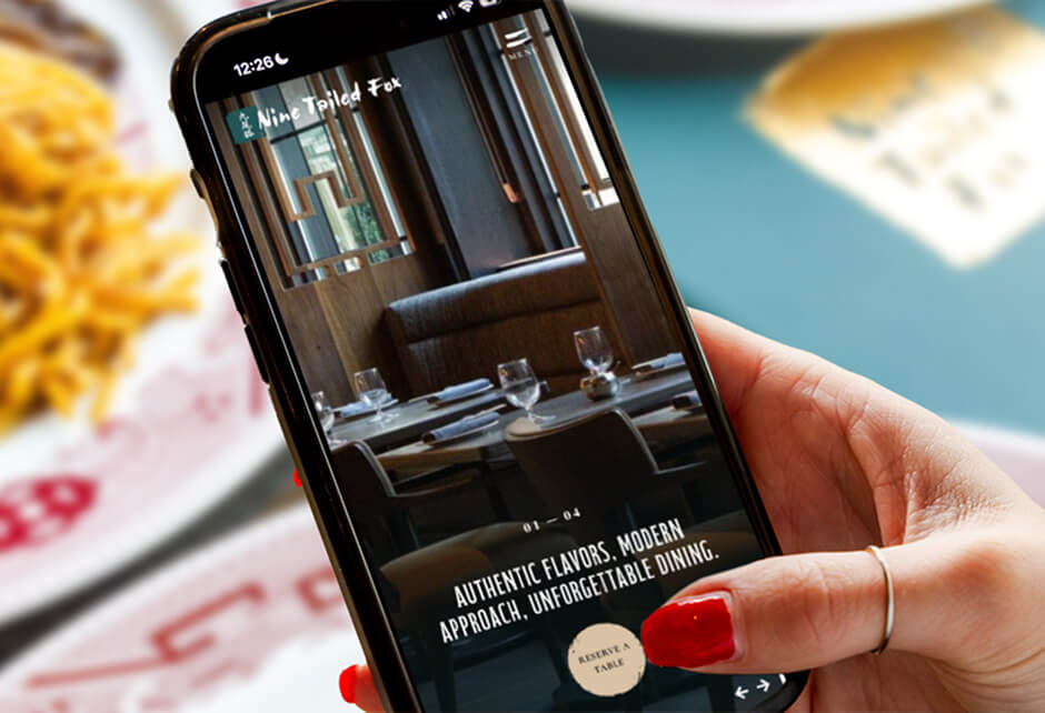 A hand holding a smartphone displays a restaurant website featuring a photo of a modern dining area and the text: Authentic flavors. Modern approach. Unforgettable dining.