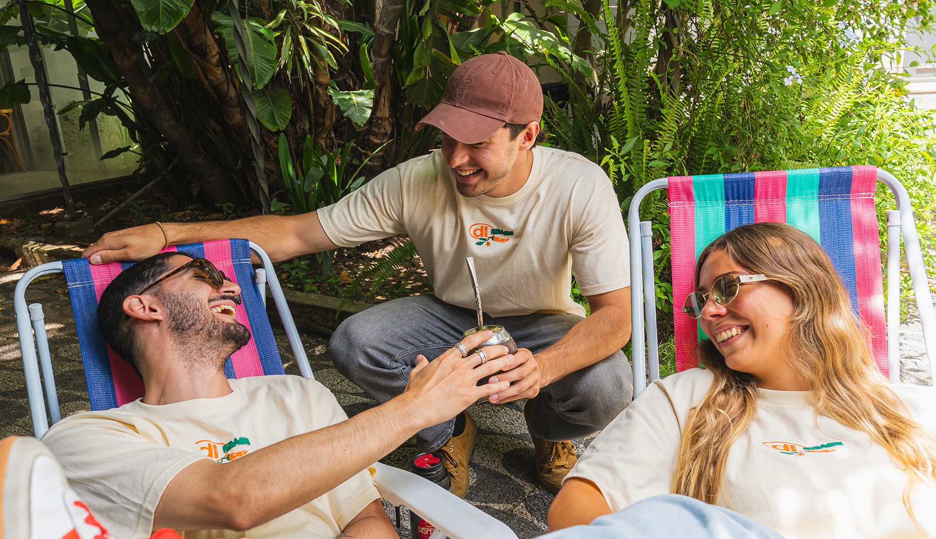 Coworkers comparten un mate sentados en sillas de playa con árboles de fondo