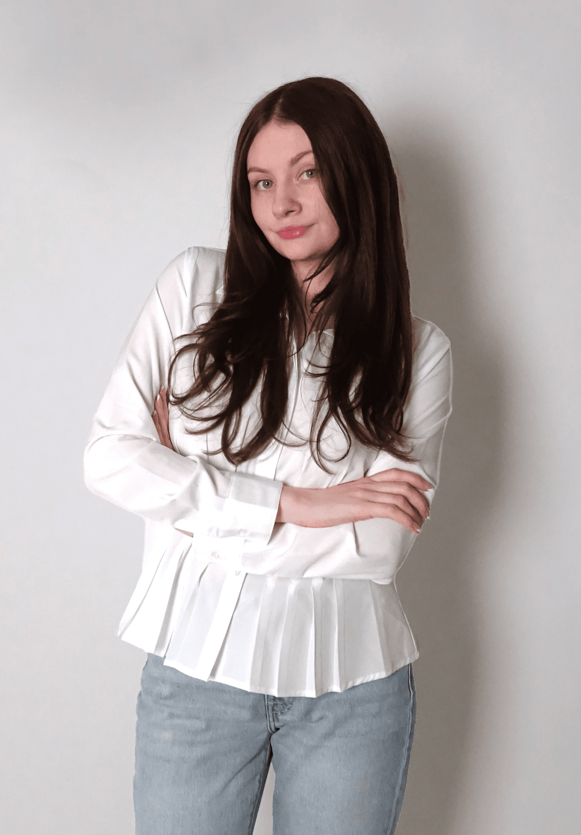 A person with long purple hair holds a camera in front of a colorful pink and red abstract background.