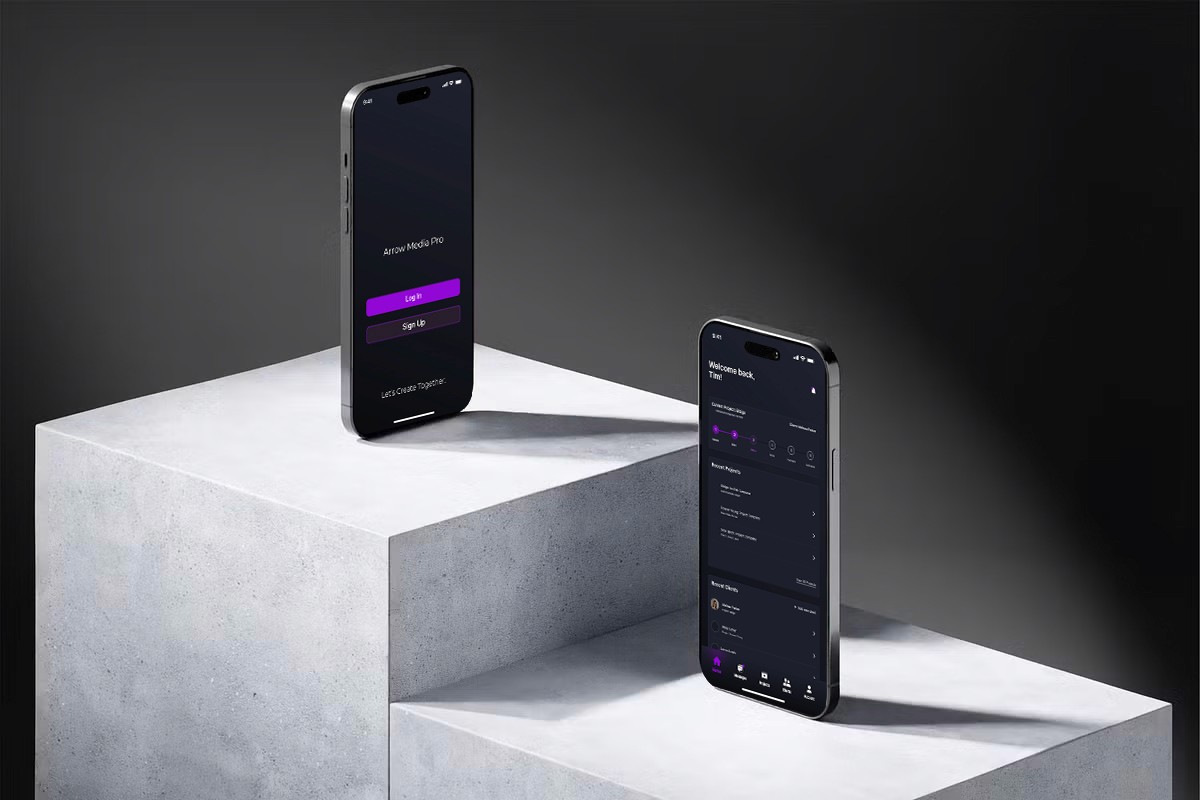 Two smartphones showing screens of a media production app, standing vertically on pieces of stone in front of a grey background