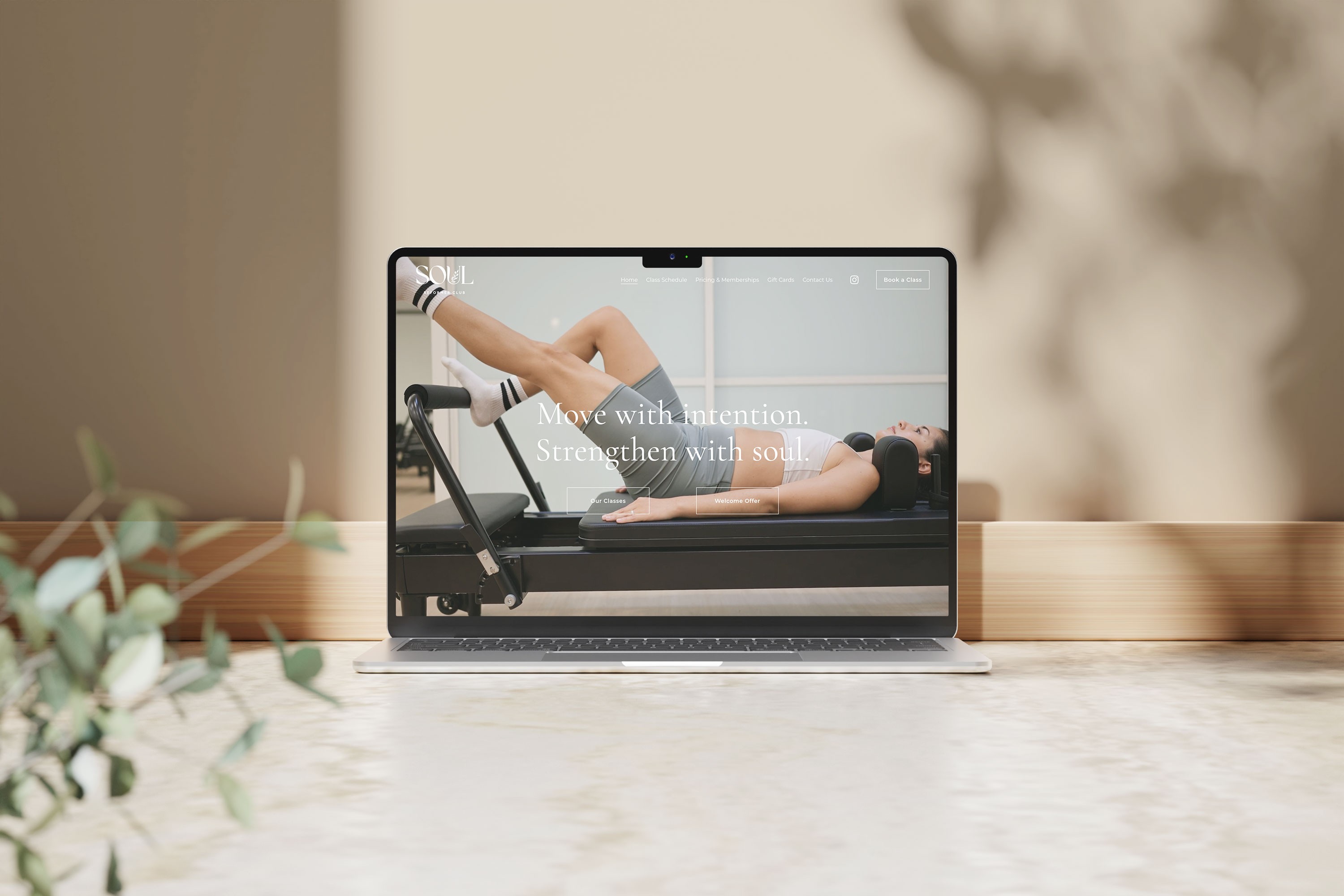 Laptop showing website with woman on reformer