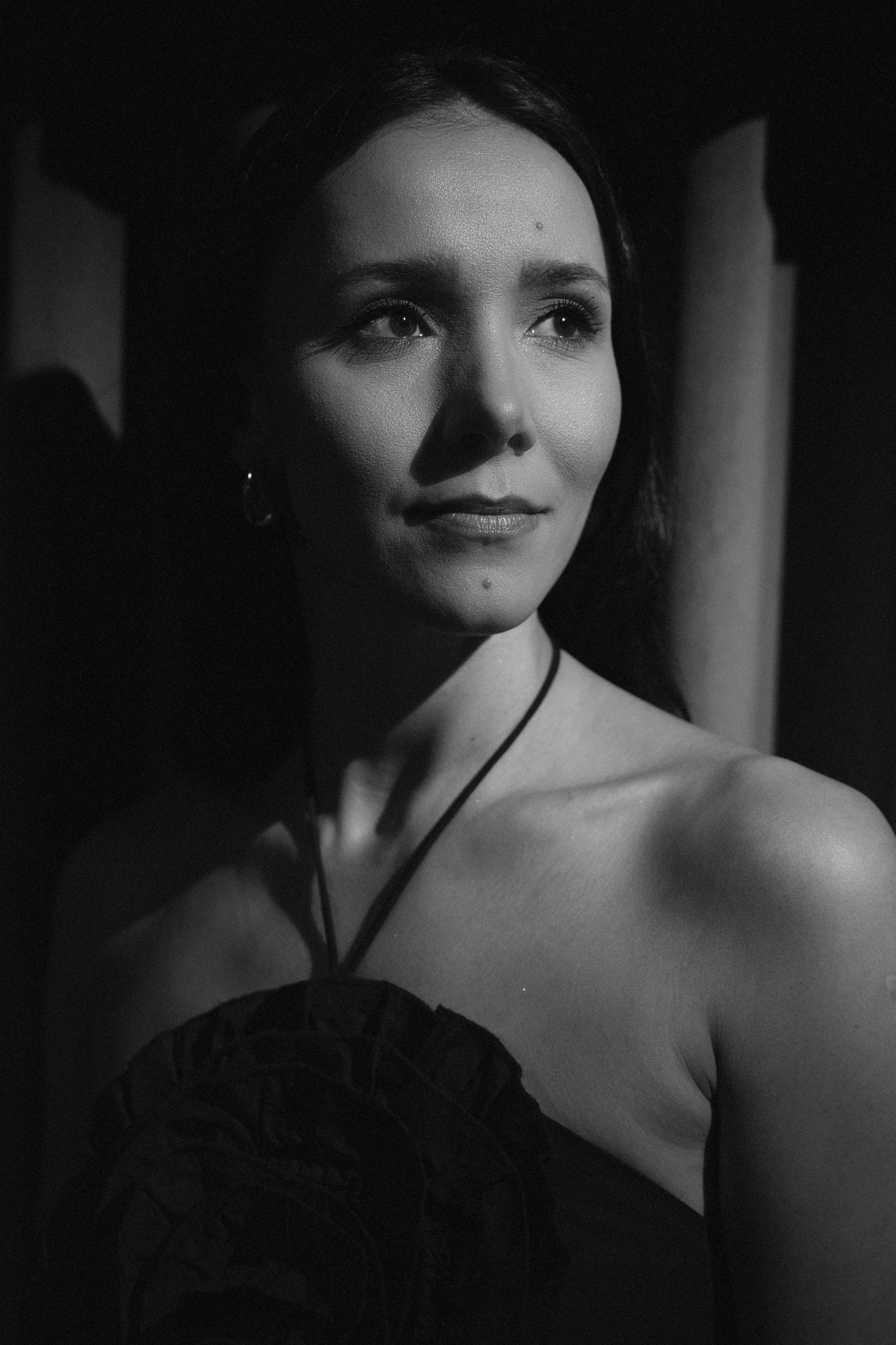 Artystyczny portret członkini Acoustic Shapes w czarno-białej tonacji, spoglądającej w bok w nastrojowym oświetleniu, co podkreśla subtelność i emocjonalny charakter muzyki.