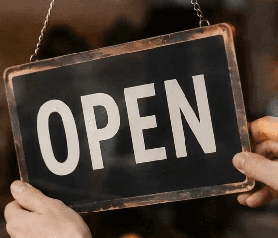 Small business owner flipping an OPEN sign at an Ontario storefront after overcoming a financial dispute