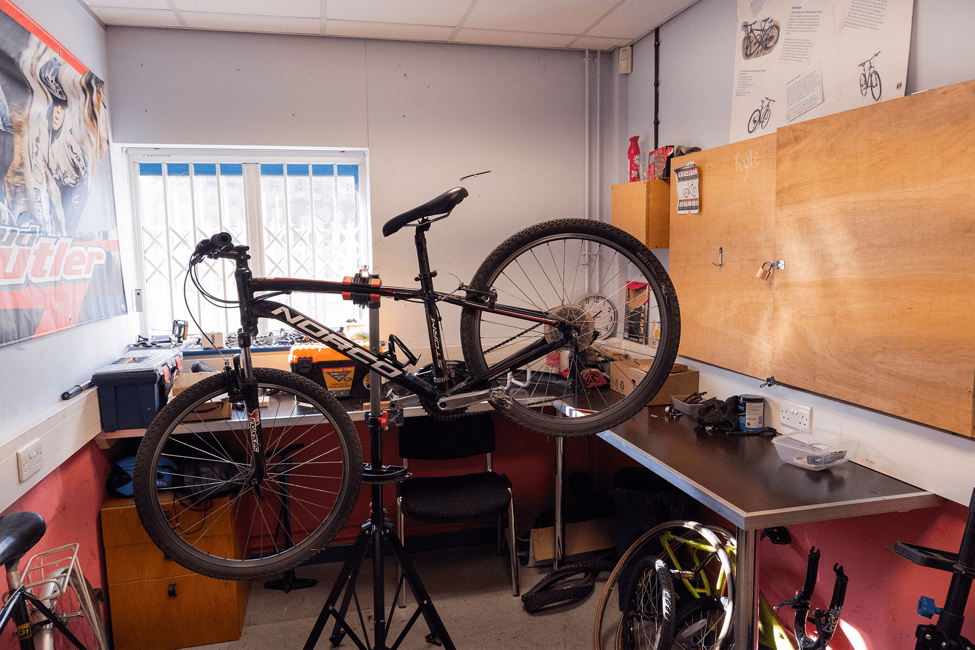 Bicycle placed in the workshop, surrounded by tools and repair equipment, indicating maintenance or repair in progress