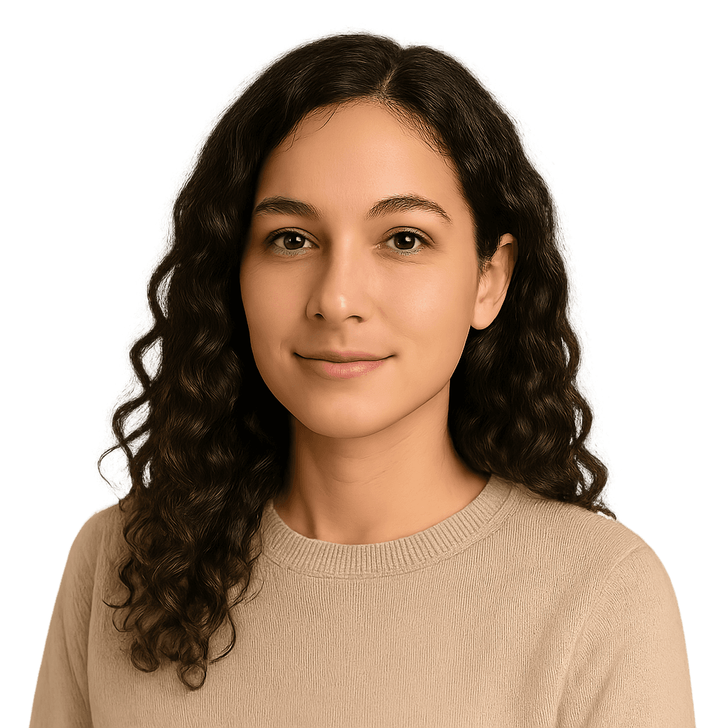 Smiling woman with curly brown hair wearing a light tan sweater. She is looking at the camera.